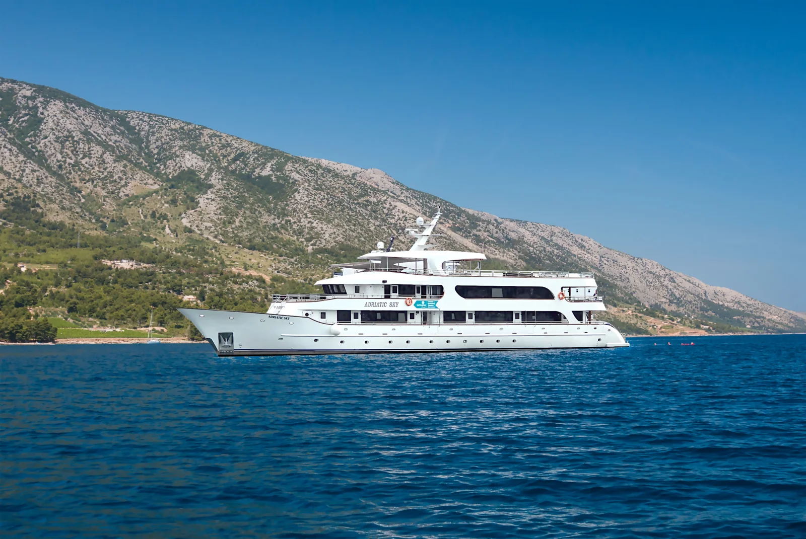 Adriatic Sky Luxury Yacht Anchored A sophisticated white luxury motor yacht named Adriatic Sky is anchored in crystal-clear blue