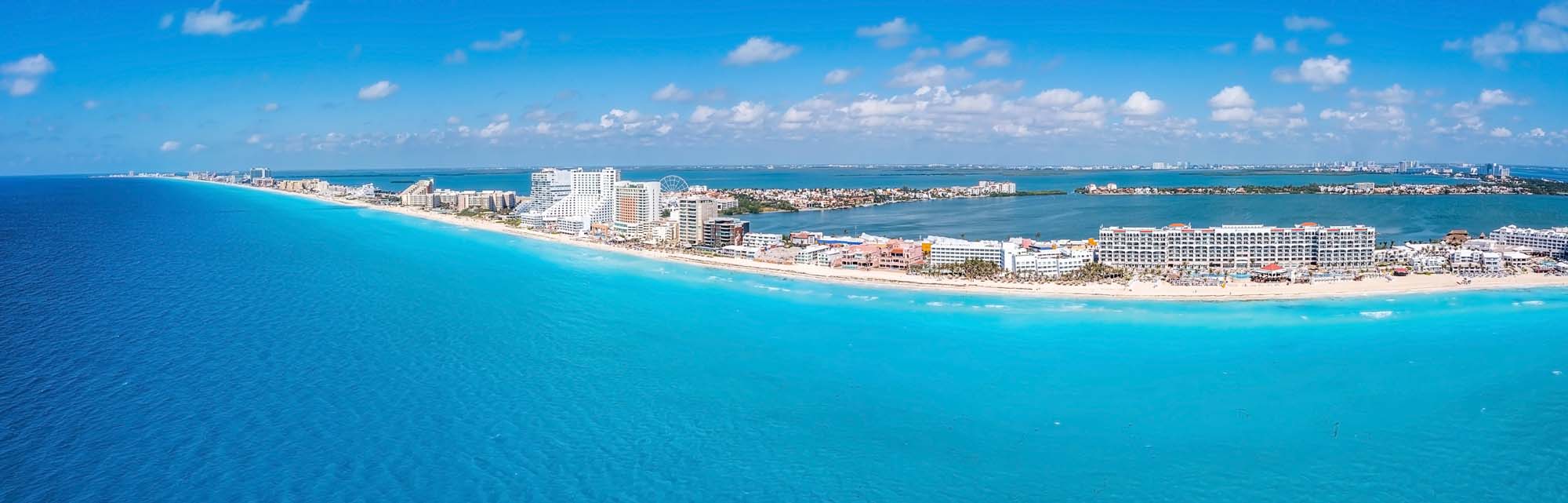 Cancun Beach and Hotel Zone Aerial View A panoramic aerial view of Cancun's stunning coastline, featuring turquoise waters, white sandy beaches, and a dense line of high-rise hotels and resorts along the shoreline.