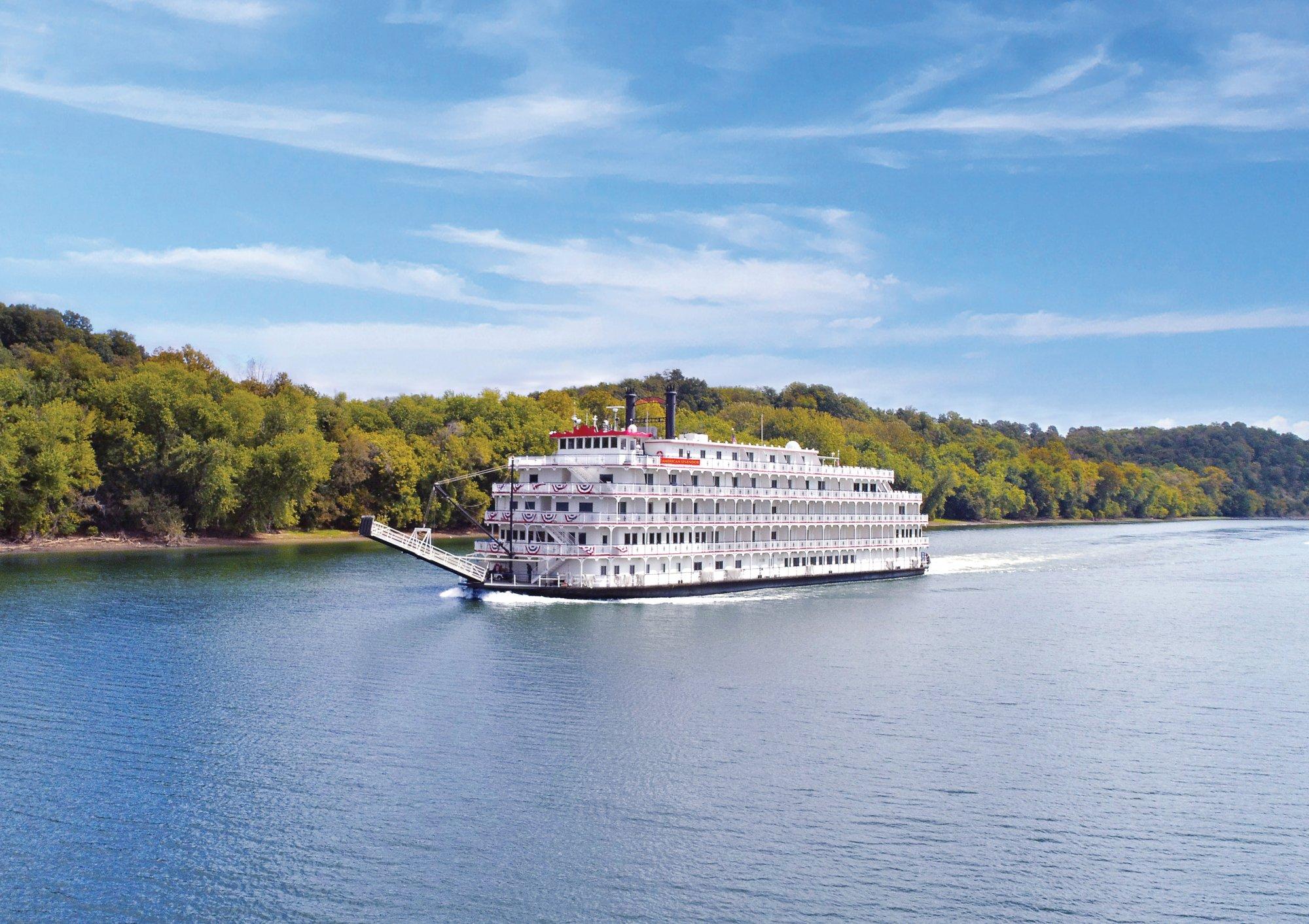 American Splendor Riverboat on Scenic River A classic American riverboat with white multi-deck architecture and red trim navigates a scenic