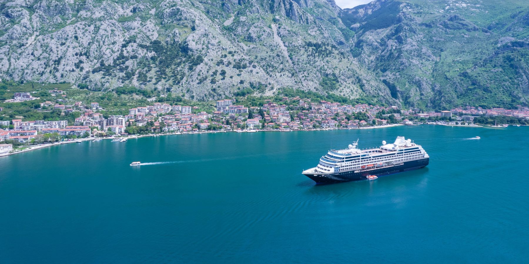 Luxury Cruise Ship in Adriatic Fjord A modern luxury cruise ship anchors in crystal-clear turquoise waters of a dramatic Adriatic fjord