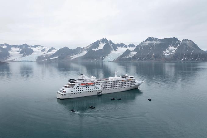 Cruise Ship in Glacial Alaskan Fjords A white cruise ship navigating through calm, reflective waters surrounded by snow-capped