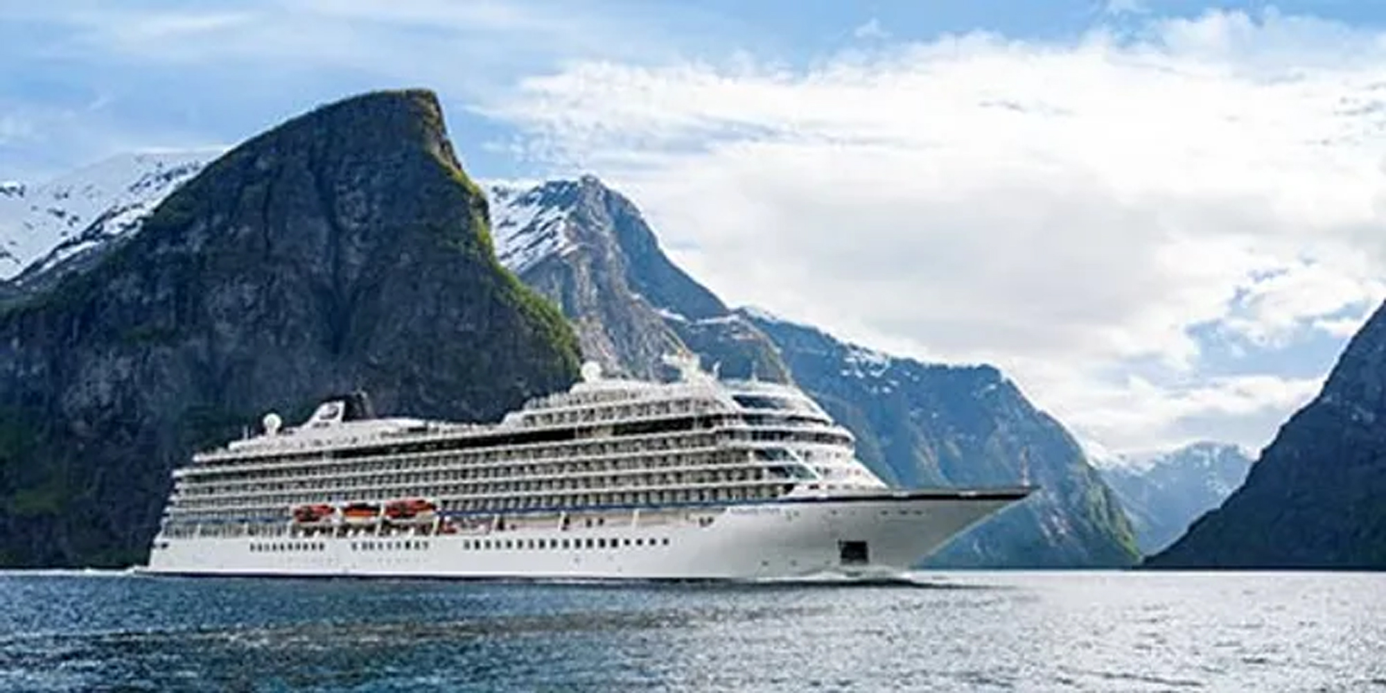 A large modern cruise ship navigates through a dramatic Norwegian fjord, surrounded by towering