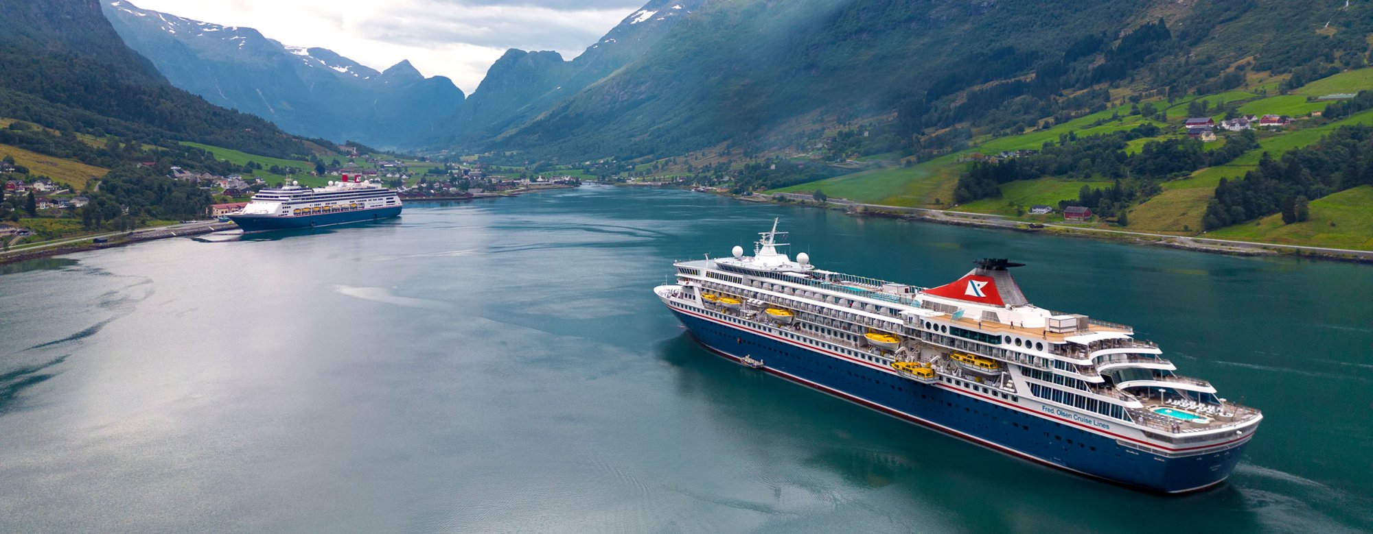 Cruise Ships in Norwegian Fjord Valley Two large cruise ships anchored in a pristine turquoise fjord surrounded by dramatic snow-capped