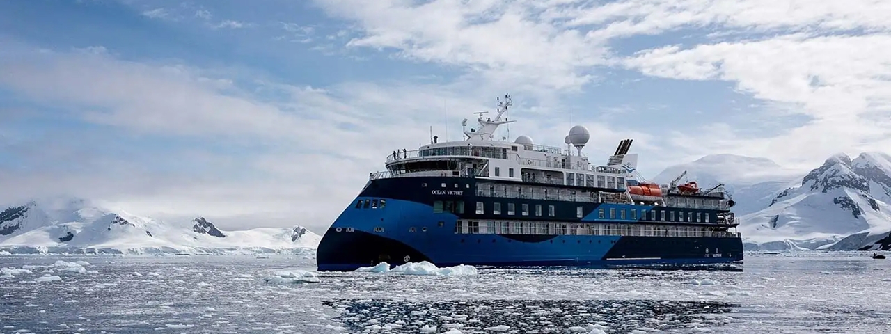 Ocean Victory Expedition Cruise Ship in Antarctica A modern expedition cruise ship with distinctive blue hull navigates through Antarctic waters