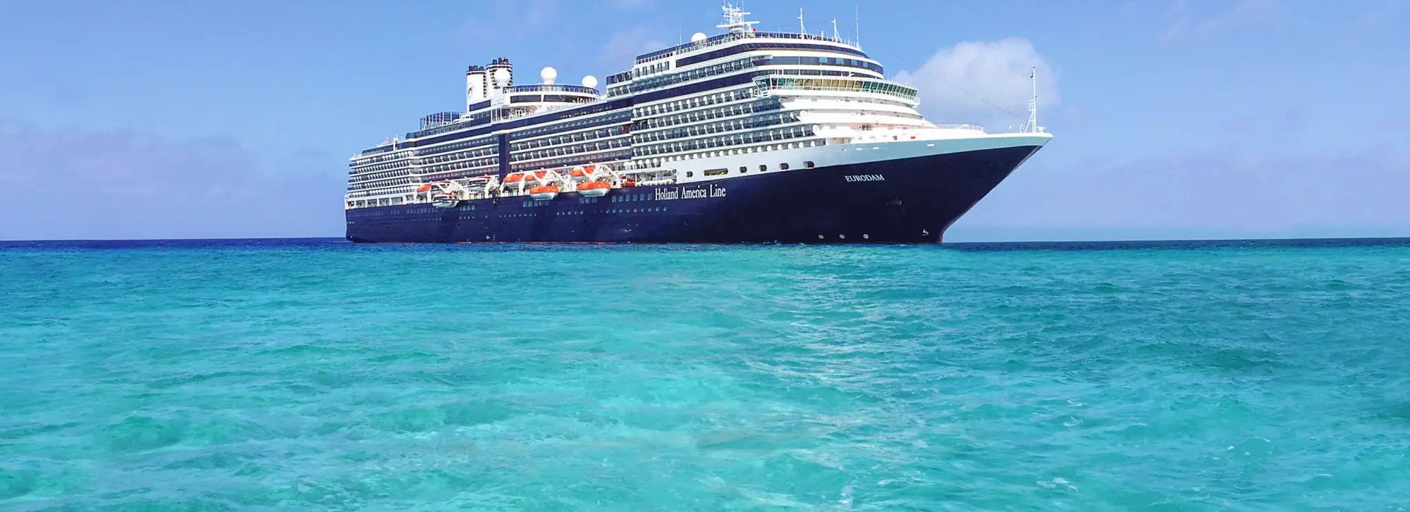 Holland America Cruise Ship at Sea A large blue and white Holland America cruise ship sailing on turquoise Caribbean waters under