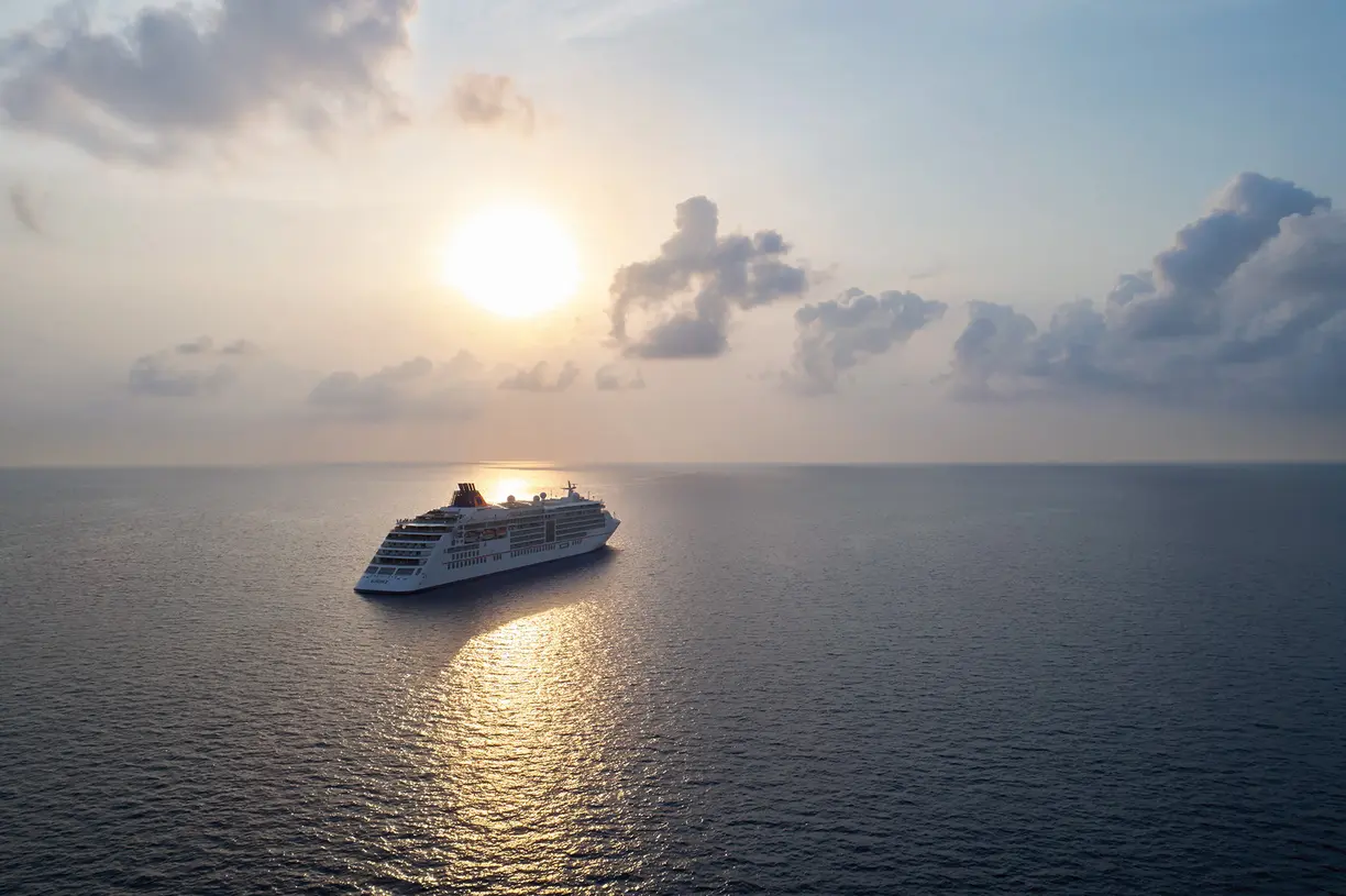 Luxury Cruise Ship at Sunrise A large modern cruise ship floats peacefully on calm blue ocean waters during golden hour, with