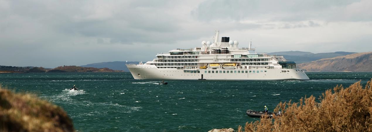 Luxury Cruise Ship in Turquoise Waters A large modern cruise ship anchored in bright turquoise waters with rocky coastline and mountains