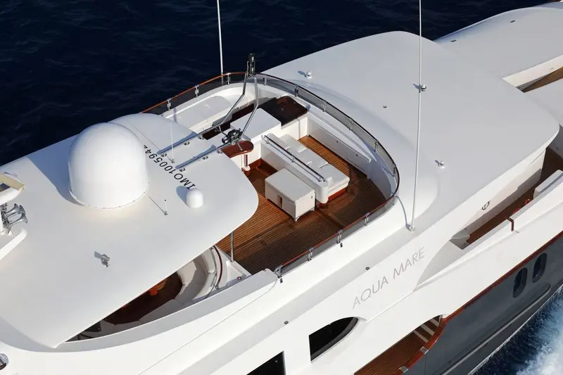 Luxury Motor Yacht Aerial Deck View Aerial view of a sleek white motor yacht with teak wood furnishings and sun loungers on the upper