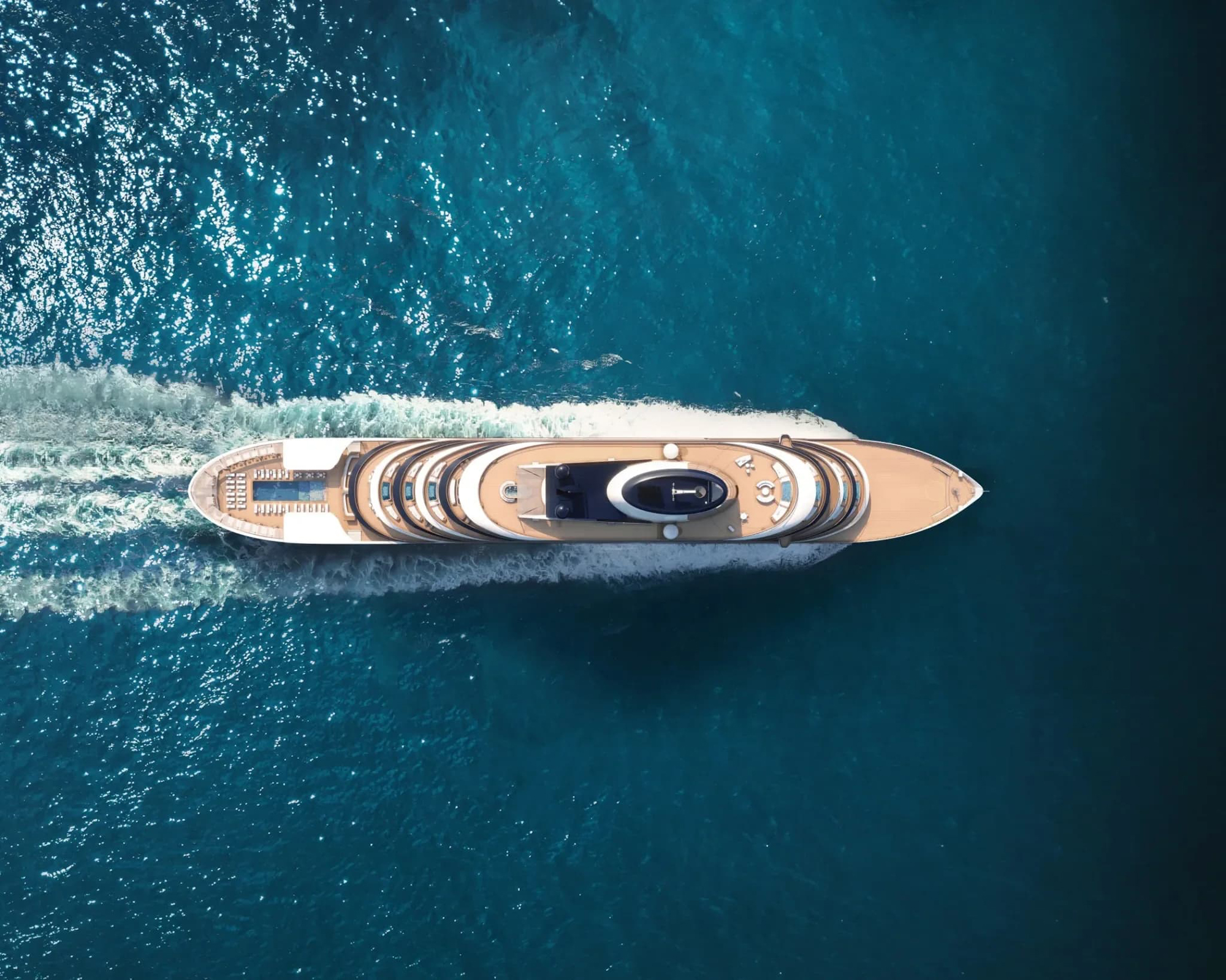 An overhead aerial view of a sleek, modern luxury yacht with distinctive tan and white design