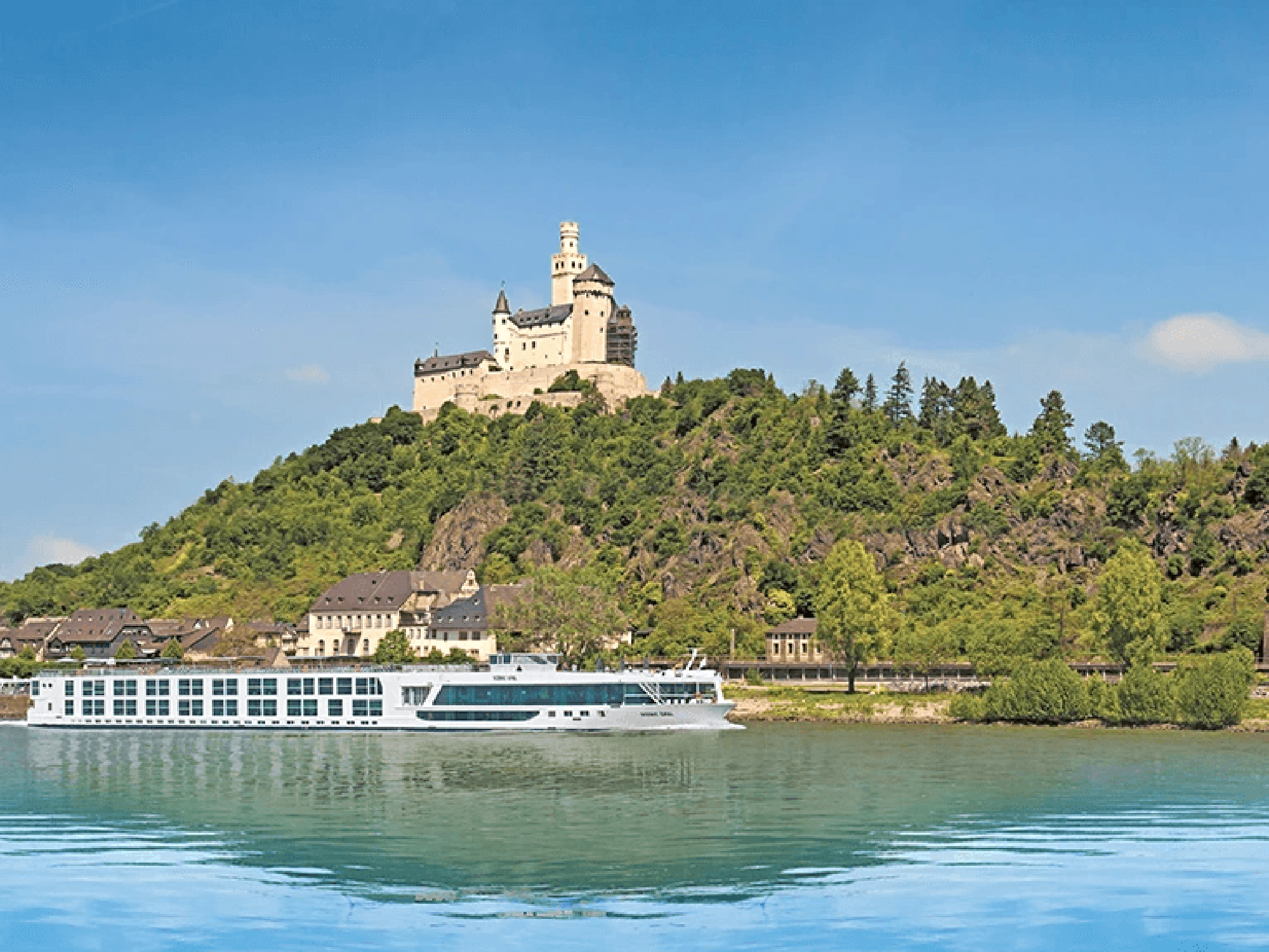 A scenic river cruise ship passes beneath the iconic Marksburg Castle, a medieval fortress perched