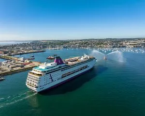 Modern Cruise Ship Departing San Diego Port A large modern cruise ship with distinctive blue funnel markings navigates the turquoise waters