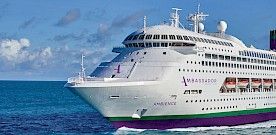 Modern Cruise Ship at Tropical Port A large modern cruise ship with distinctive purple hull and white superstructure is docked at