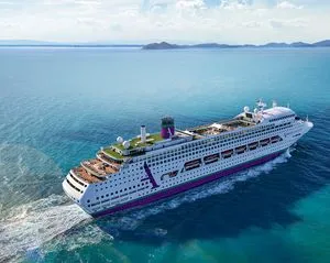 Modern Cruise Ship in Tropical Waters A large modern cruise ship navigates crystal-clear turquoise waters near a tropical island