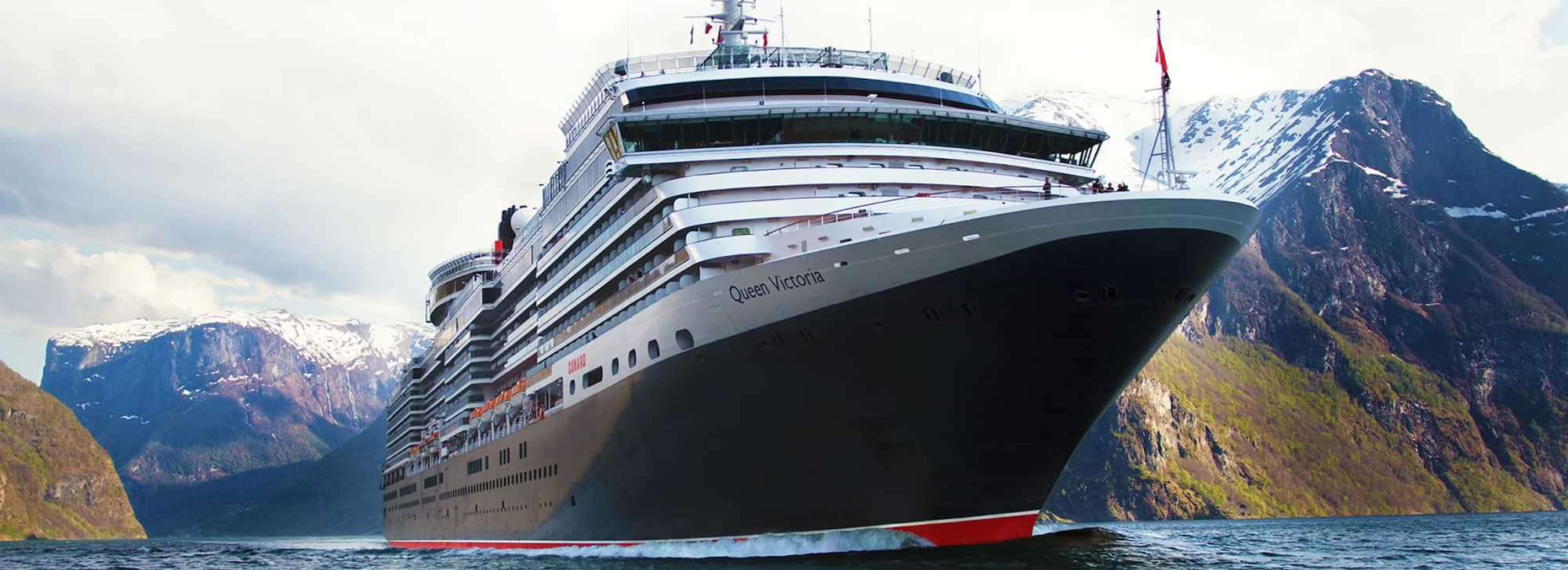 Queen Victoria Cruise Ship in Fjord Landscape A large Cunard cruise ship, the Queen Victoria, sailing through a scenic fjord with snow-capped