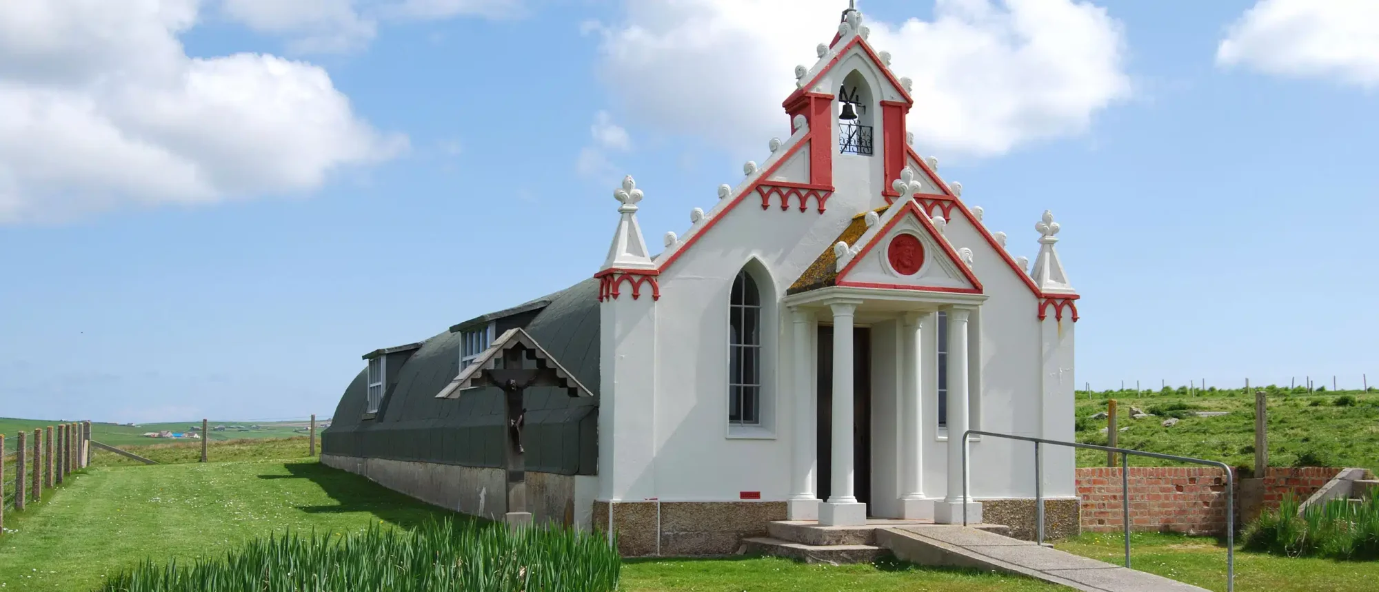 Red and White Church in Northern Isles A distinctive red and white chapel with Victorian Gothic architecture stands in an open, windswept