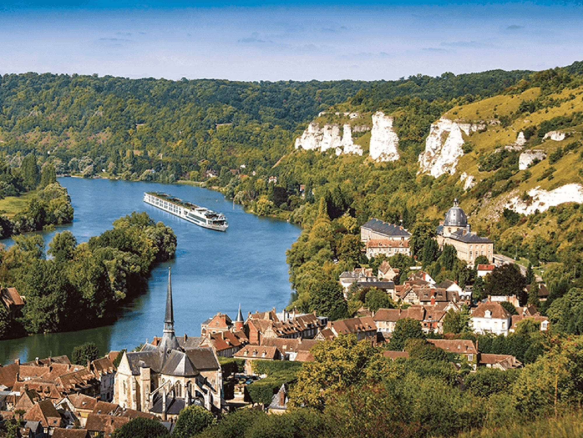 A scenic river cruise ship navigates through the picturesque Seine River valley near Les Andelys