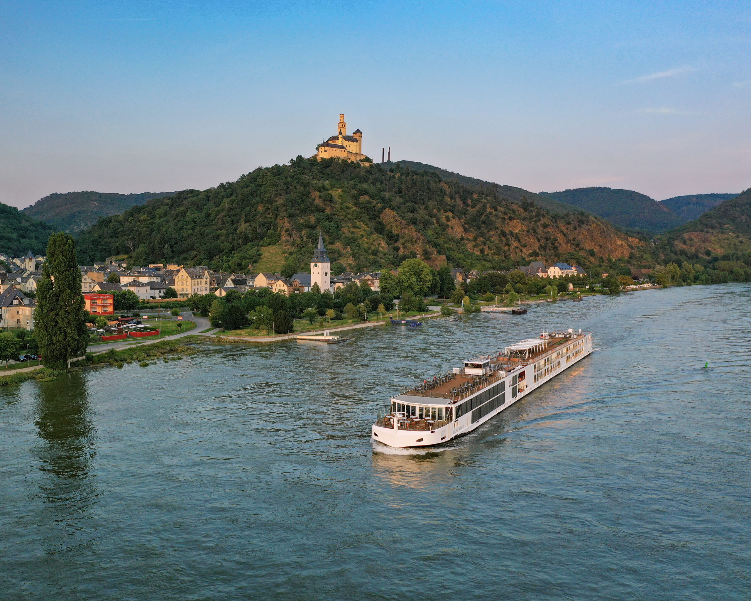 River Cruise Ship at Braubach with Marksburg Castle A scenic river cruise ship navigates past the charming town of Braubach on the Rhine River