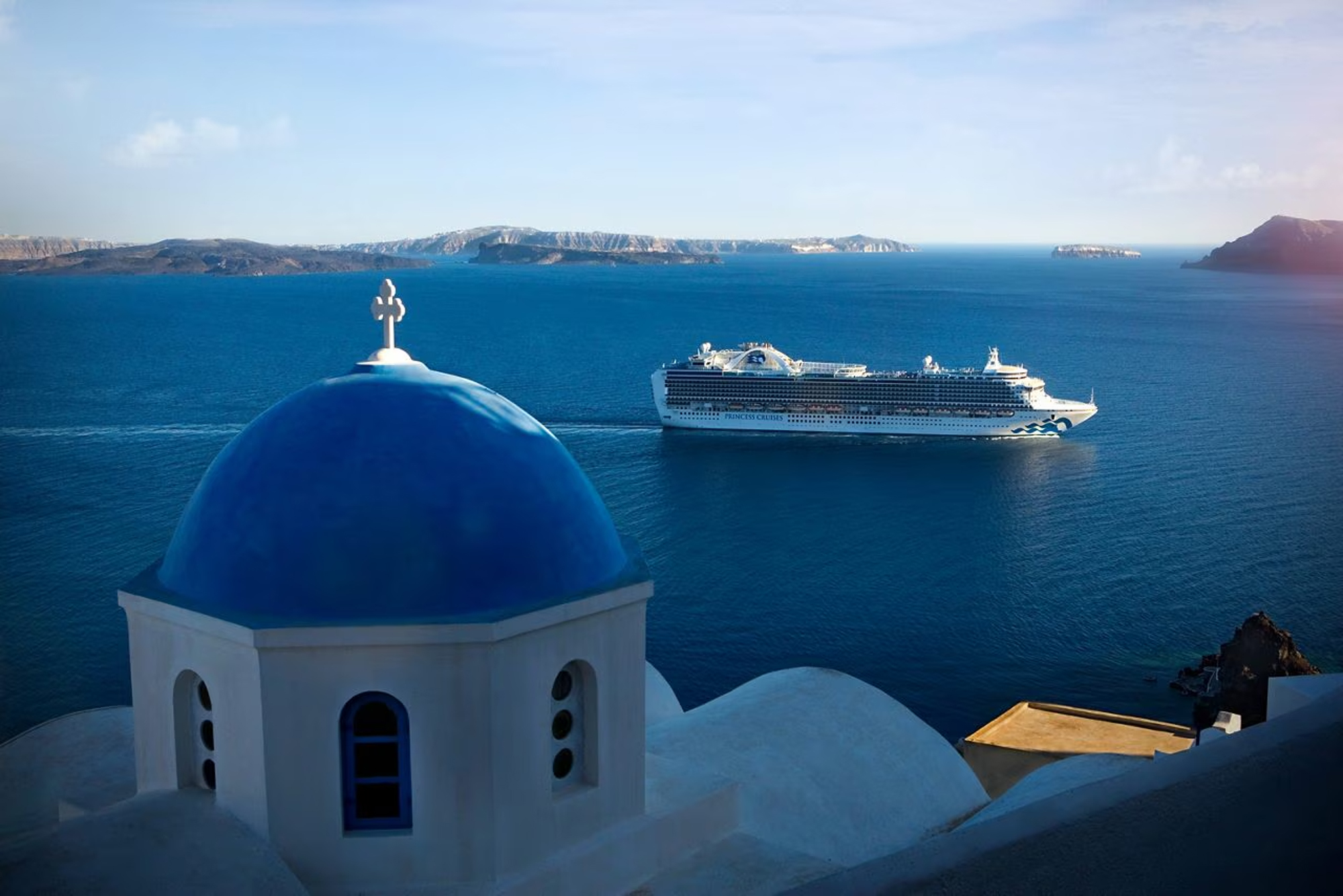 Santorini Blue Dome and Cruise Ship Vista A classic white and blue church dome overlooks a large cruise ship anchored in the deep blue waters