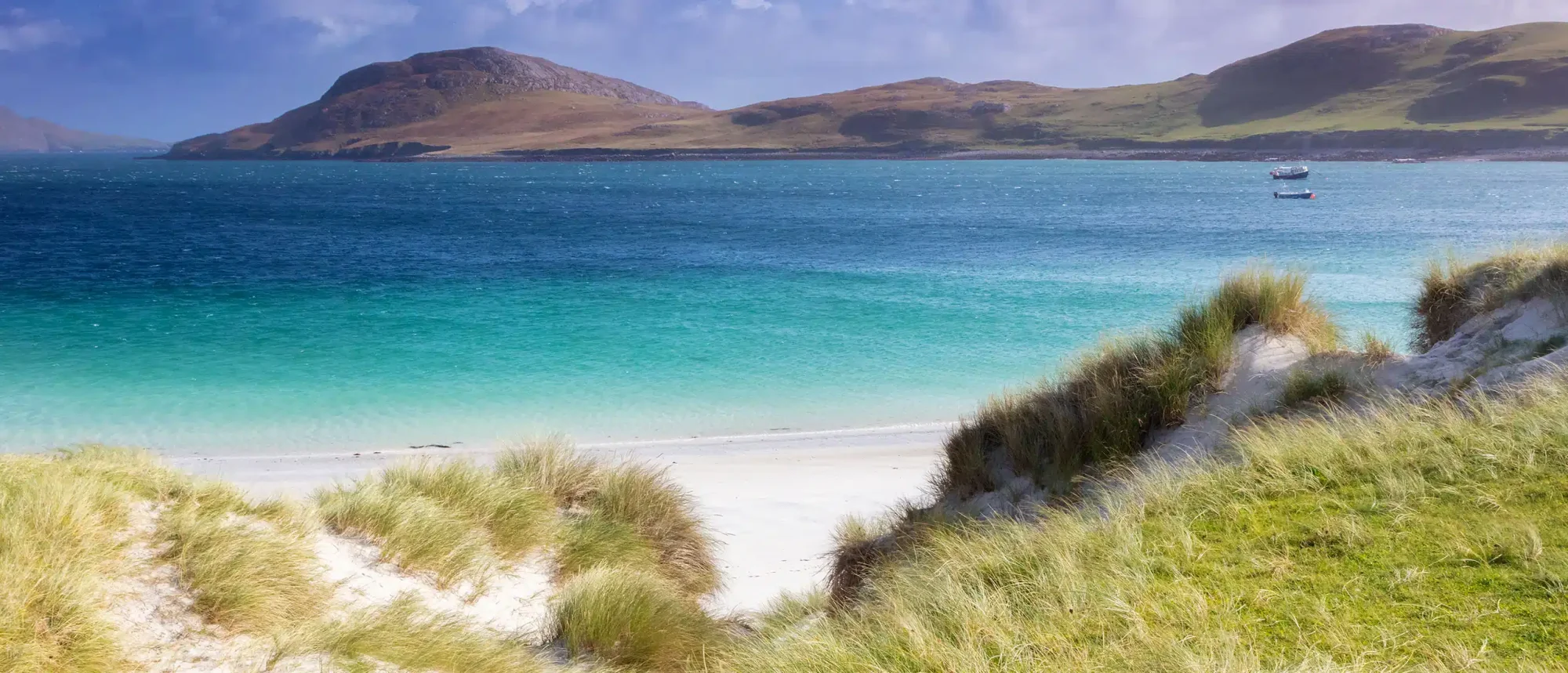 Turquoise Bay with Coastal Hills A pristine beach scene featuring crystal-clear turquoise waters, white sand, and windswept dune
