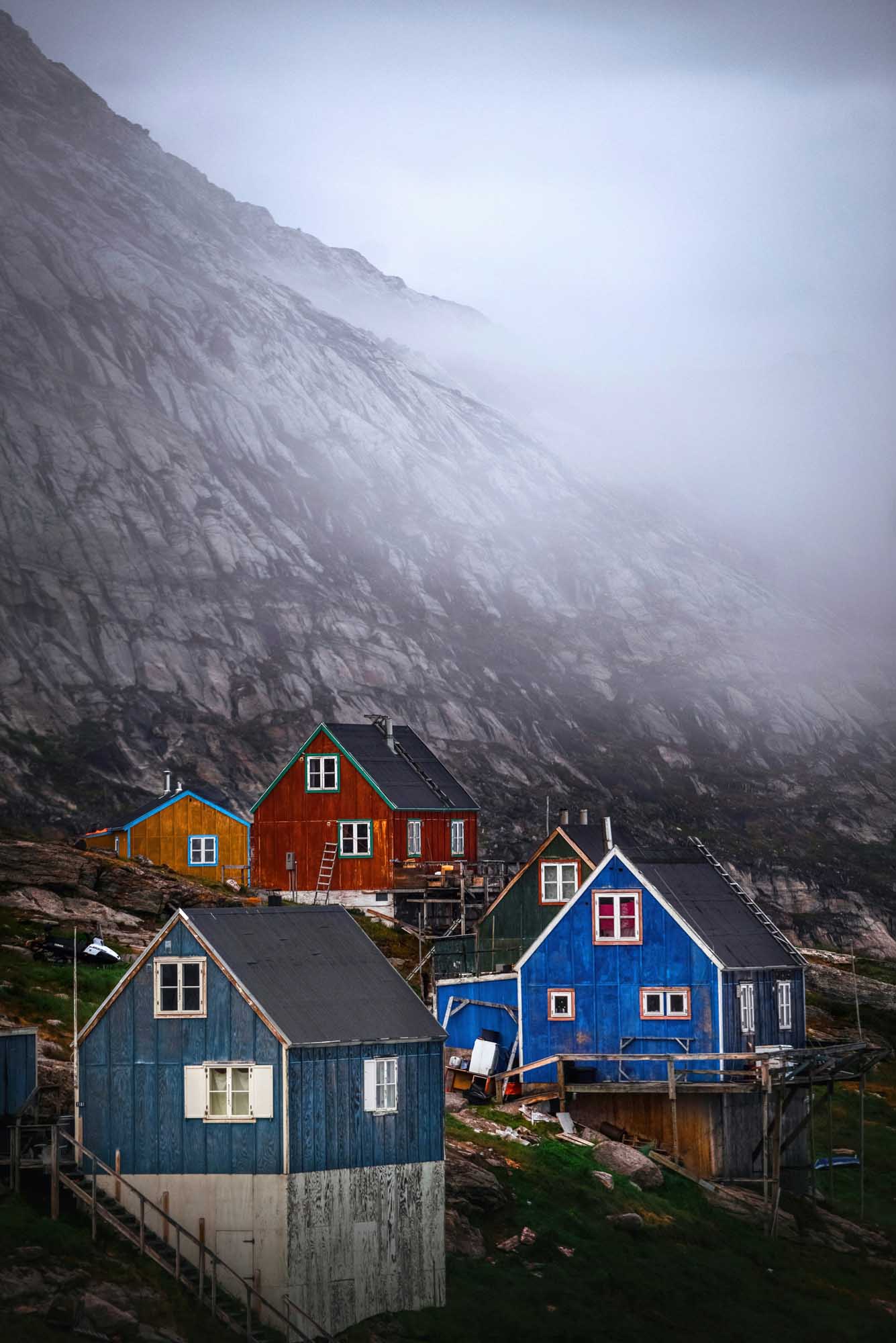 Colorful Houses Beneath Misty Arctic Cliffs A picturesque collection of brightly colored traditional houses nestled at the base of a towering