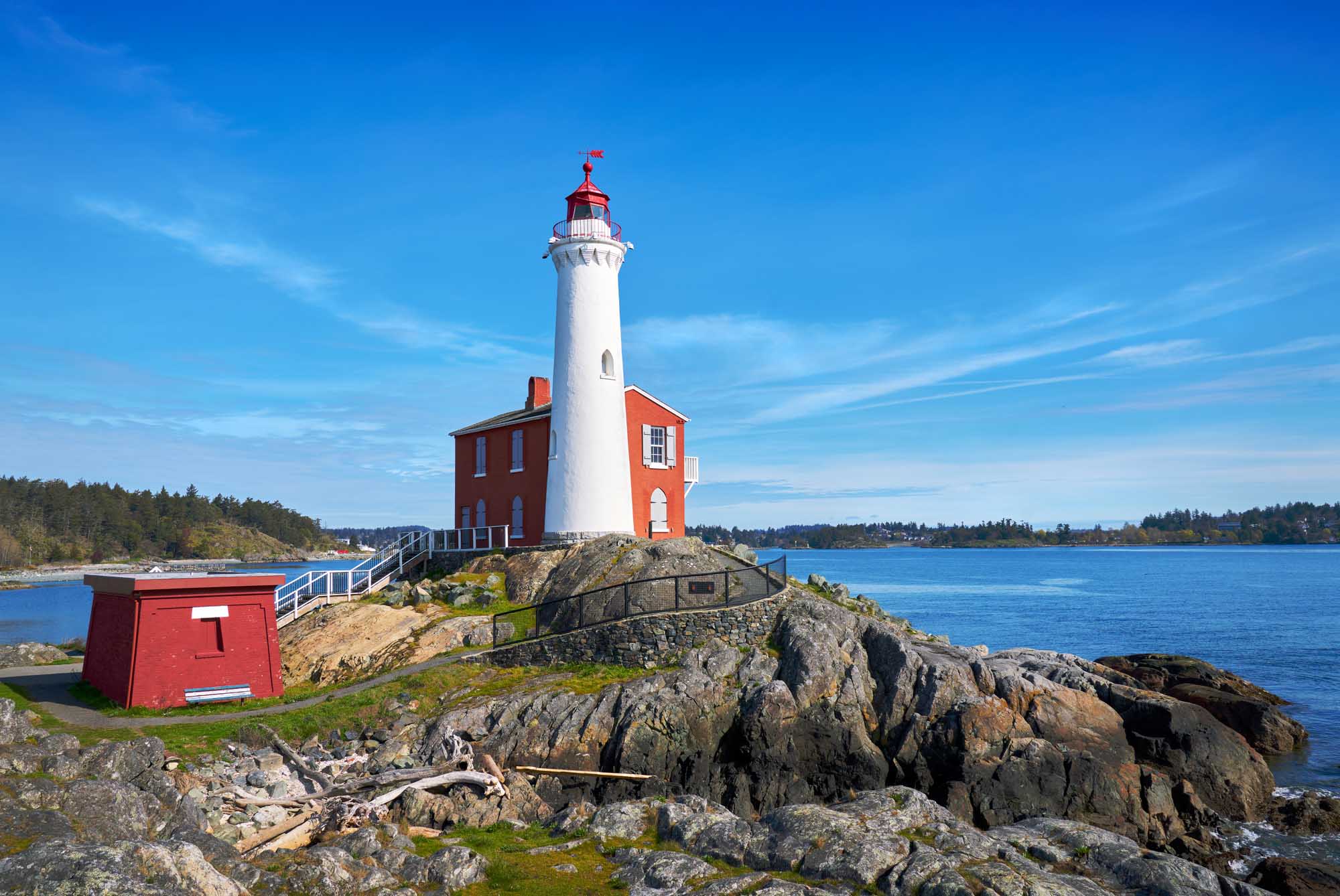 Fisgard Lighthouse Near Victoria, British Columbia A historic red and white lighthouse situated on a rocky outcropping overlooking the Strait of Juan