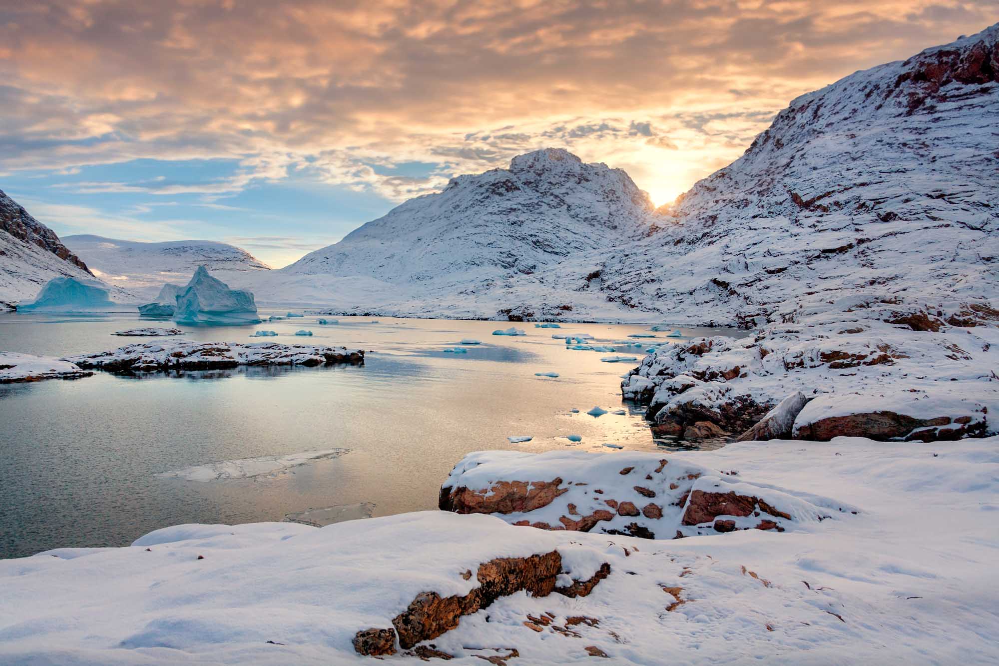 Hurry Inlet at Dusk, East Greenland A stunning Arctic landscape featuring snow-covered mountains framing a frozen inlet dotted
