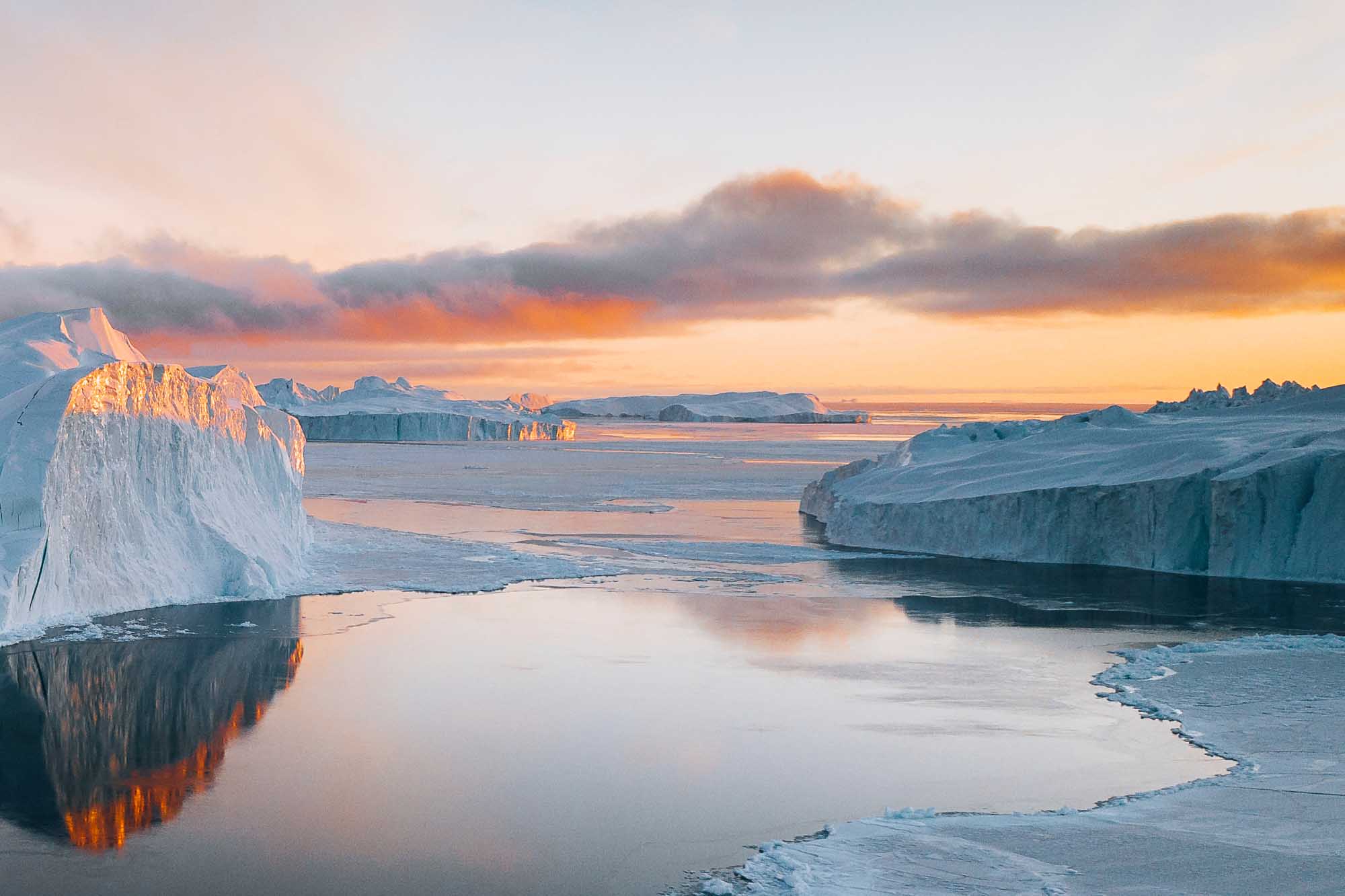 Icebergs and Frozen Sea at Arctic Sunrise A stunning arctic landscape featuring massive icebergs with white and blue hues reflected in