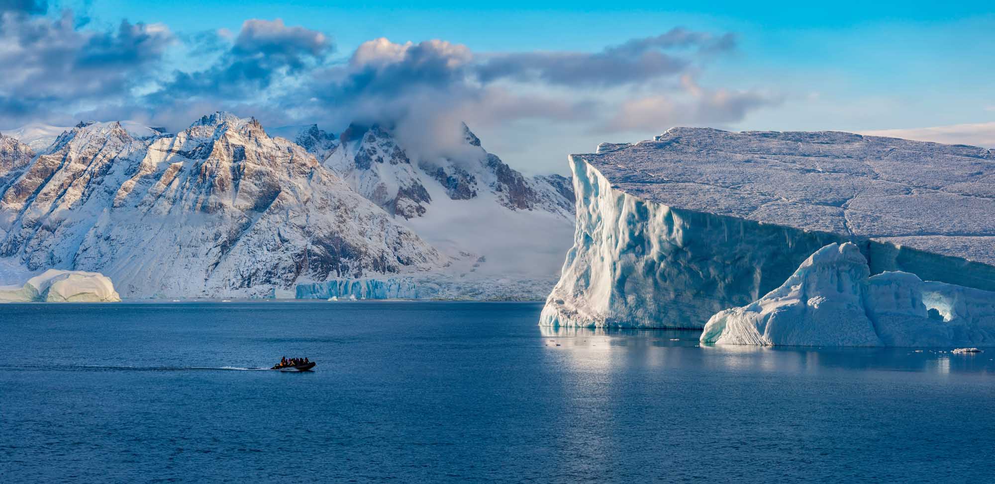 Icebergs and Mountains in Scoresbysund, Greenland A breathtaking Arctic landscape featuring towering icebergs with striking turquoise hues floating