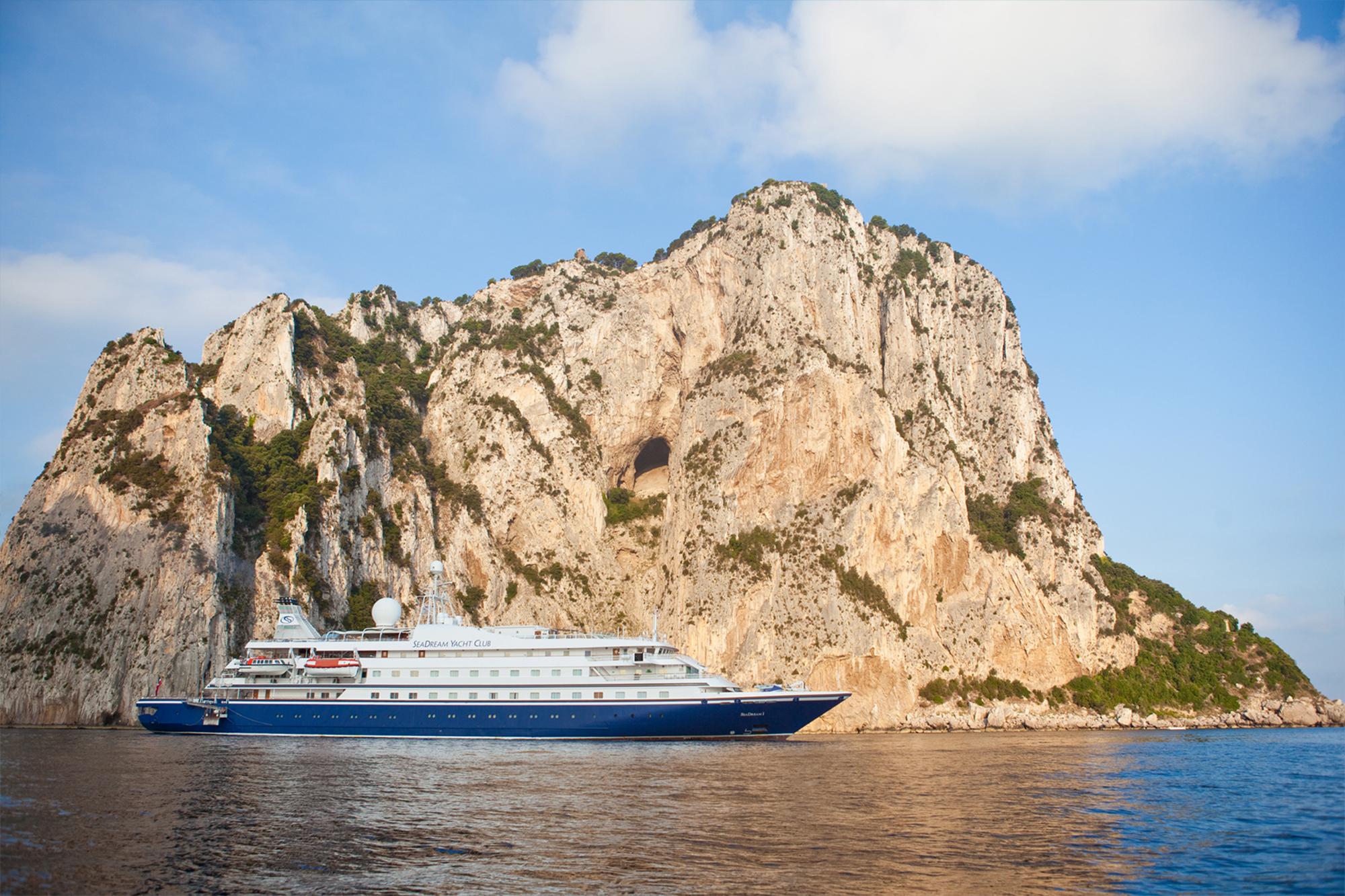 Cruise Ship at Limestone Cliff Anchorage A luxury cruise ship with blue hull and white superstructure anchored in clear Mediterranean waters
