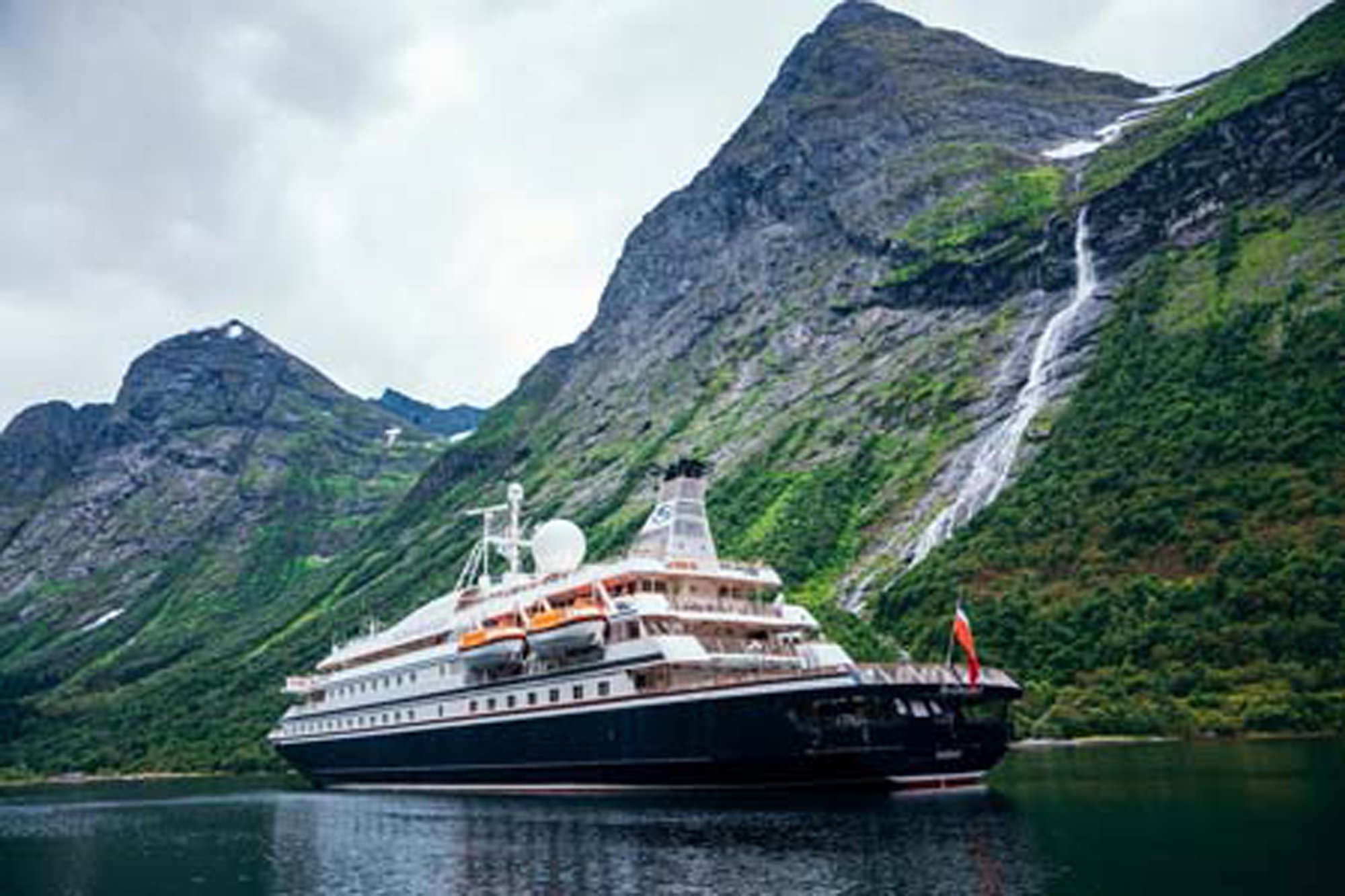 Luxury Cruise Ship in Norwegian Fjord A large expedition cruise ship anchors in a dramatic Norwegian fjord surrounded by steep, green