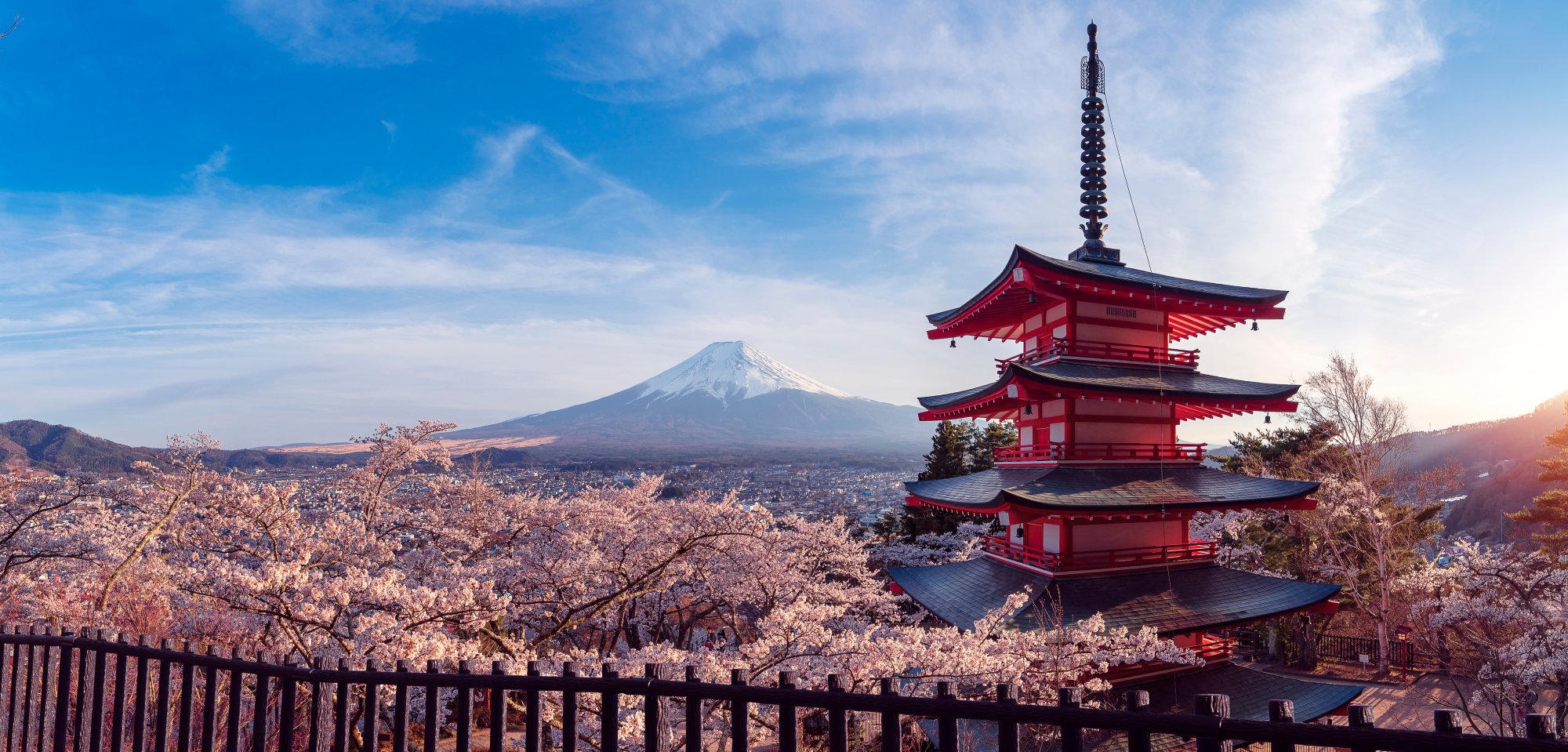 Mount Fuji and Red Pagoda at Cherry Blossom Season A stunning scenic view of a traditional red Japanese pagoda framed by cherry blossom trees in full bloom, with snow-capped Mount Fuji visible in the distance across the landscape. The composition captures the iconic beauty of Japan during spring with the pagoda's distinctive architecture prominent in the foreground.