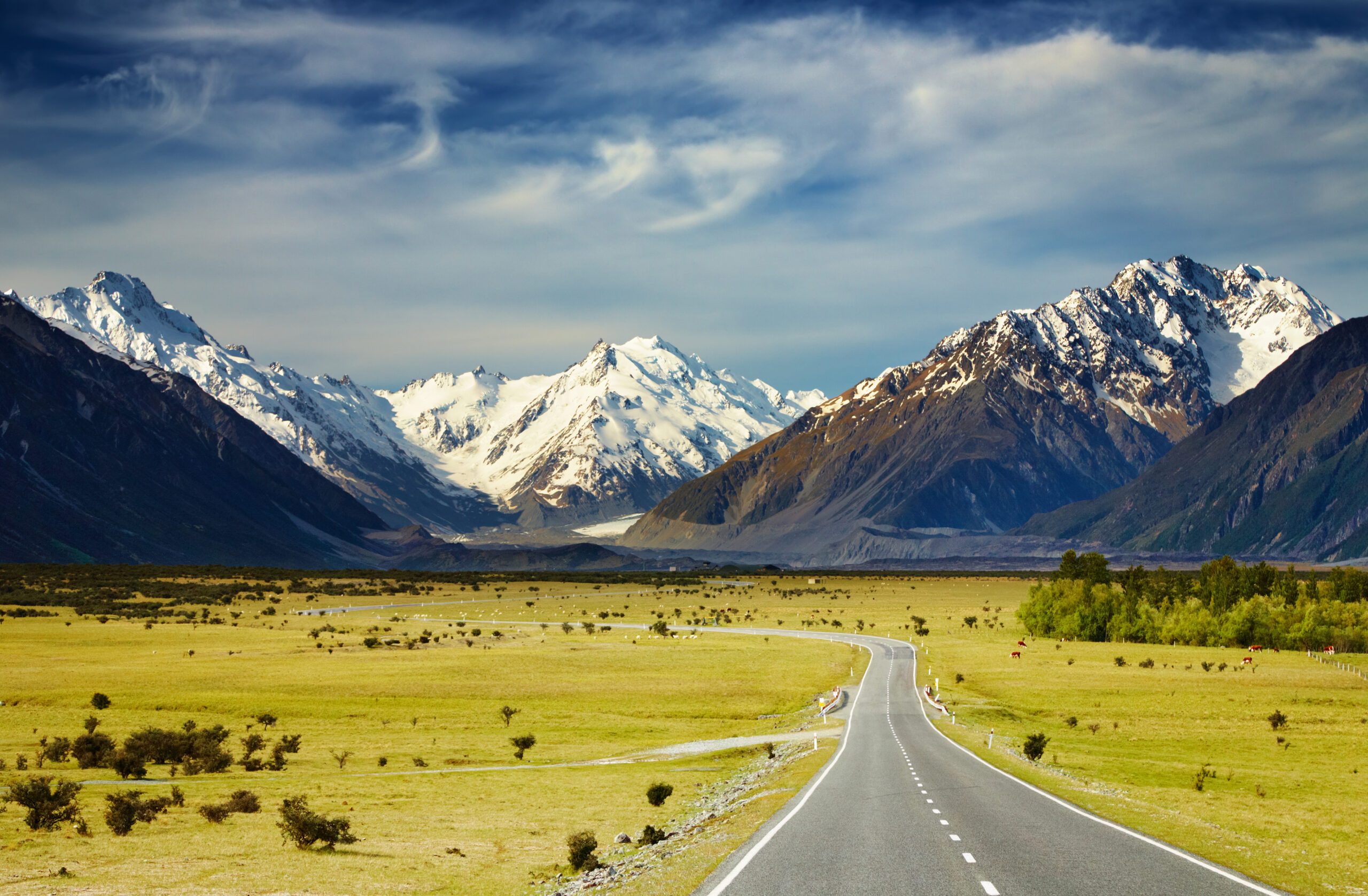 Mountain Road Through Alpine Valley A straight asphalt highway stretches through a verdant alpine valley dotted with sparse vegetation