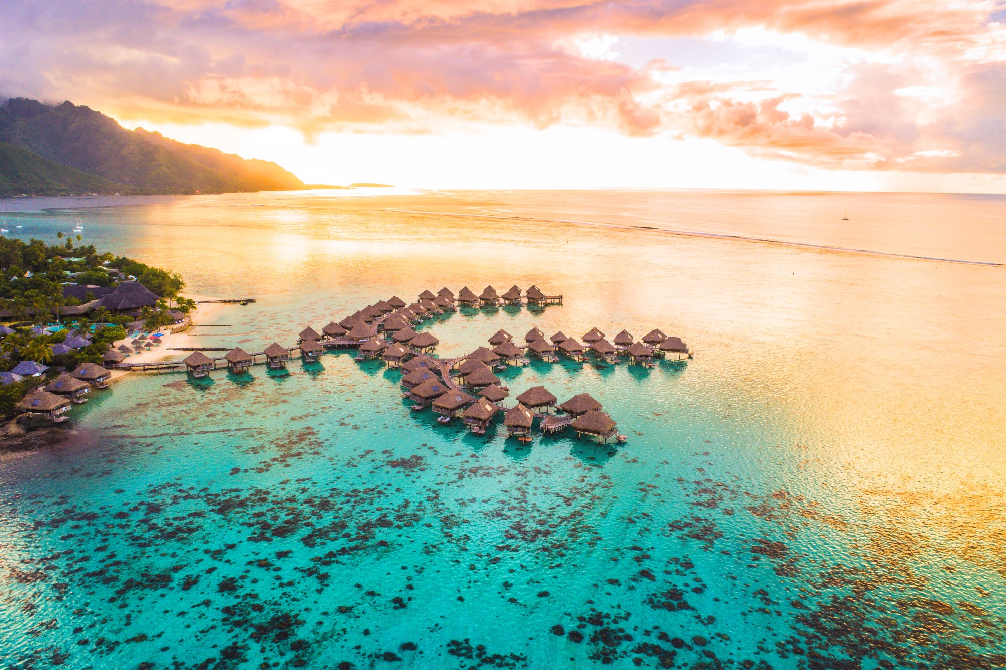 Overwater Bungalows at Tropical Sunset An idyllic tropical resort featuring traditional thatched-roof overwater bungalows arranged in