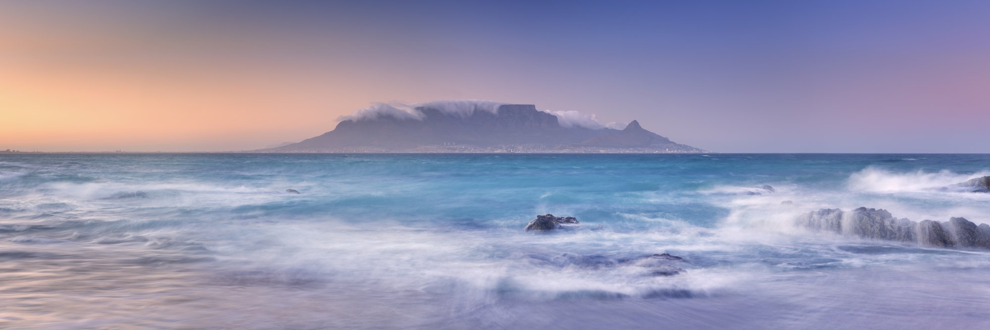 Table Mountain at Sunrise from Beach A stunning coastal landscape featuring Table Mountain shrouded in cloud cover at dawn, viewed