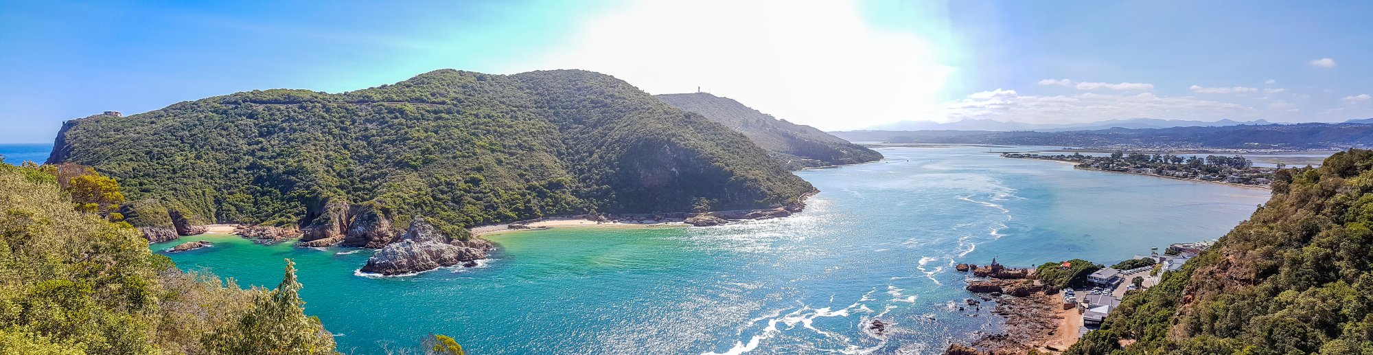 Tropical Coastal Bay with Forested Headland A stunning panoramic view of a pristine tropical coastline featuring a verdant, densely forested