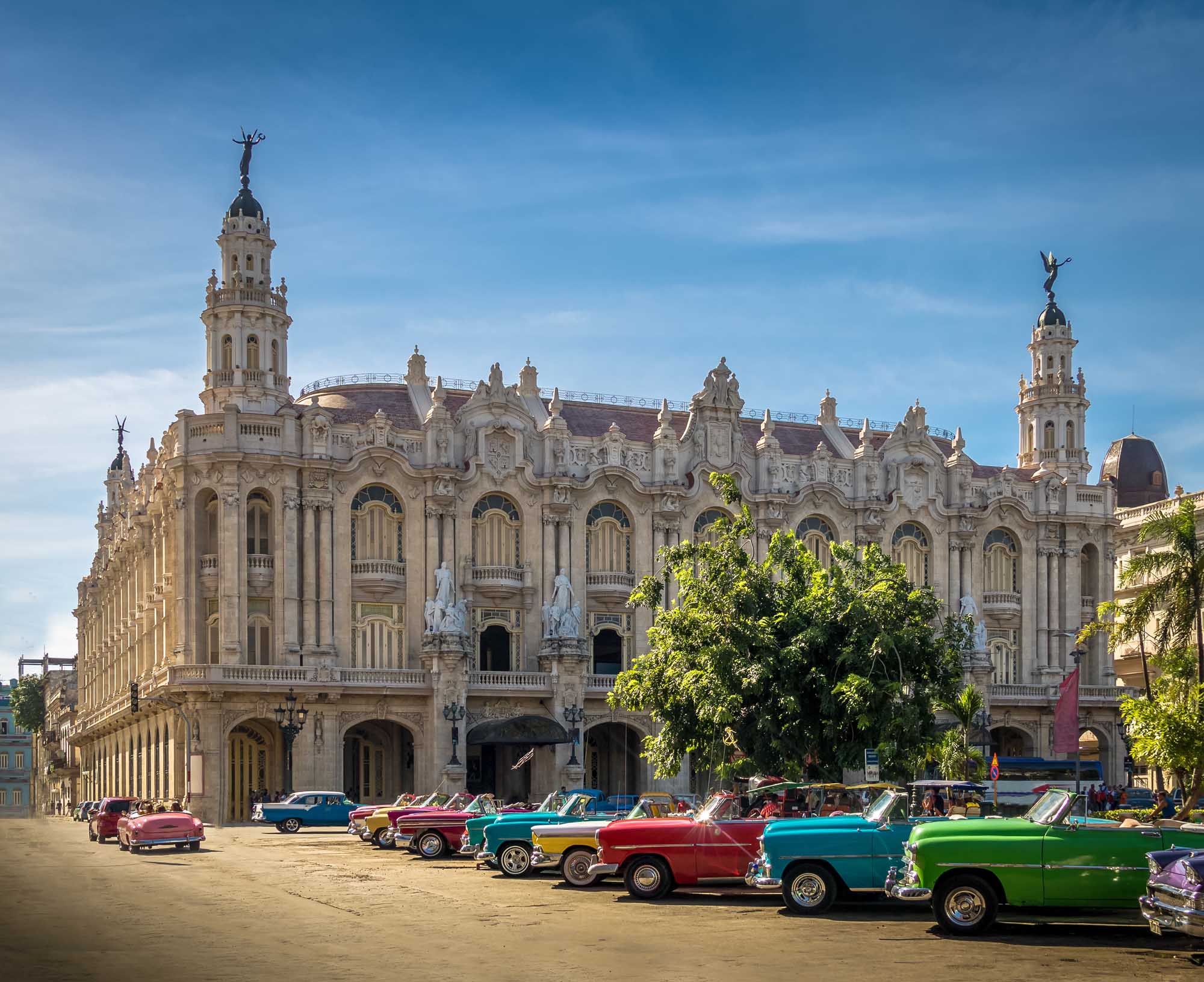 Vintage Cars at Gran Teatro de La Habana A vibrant collection of colorful 1950s American classic cars parked in front of the ornate Gran Teatro de La Habana, a stunning Baroque Revival theater building in Cuba's capital city. The scene captures the iconic street culture of Havana with its distinctive pastel-colored vintage automobiles and grand historic architecture.
