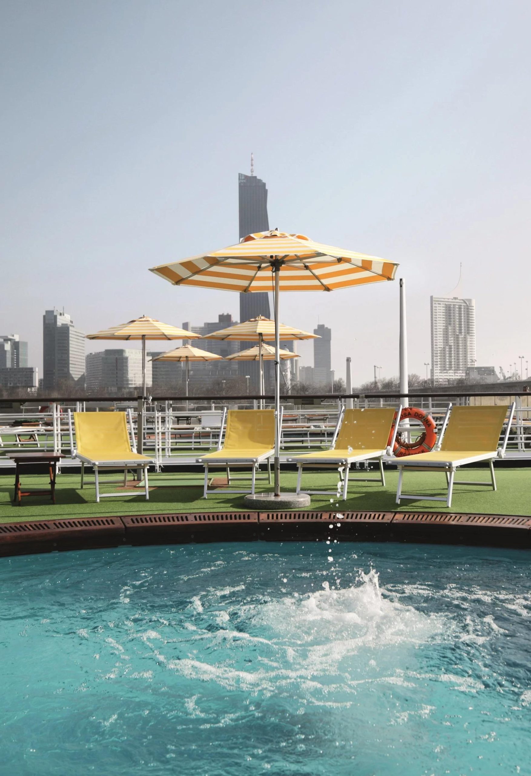 A-ROSA Cruise Ship Pool Deck with Chicago Skyline A luxurious riverside pool deck aboard an A-ROSA cruise ship, featuring turquoise waters, yellow