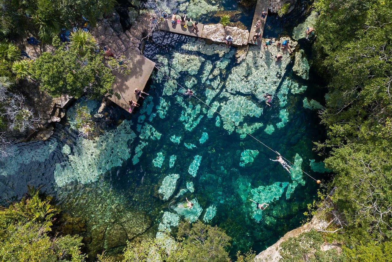 Aerial View of Azure Cenote in Mexico An overhead aerial photograph of a stunning turquoise cenote surrounded by lush jungle vegetation