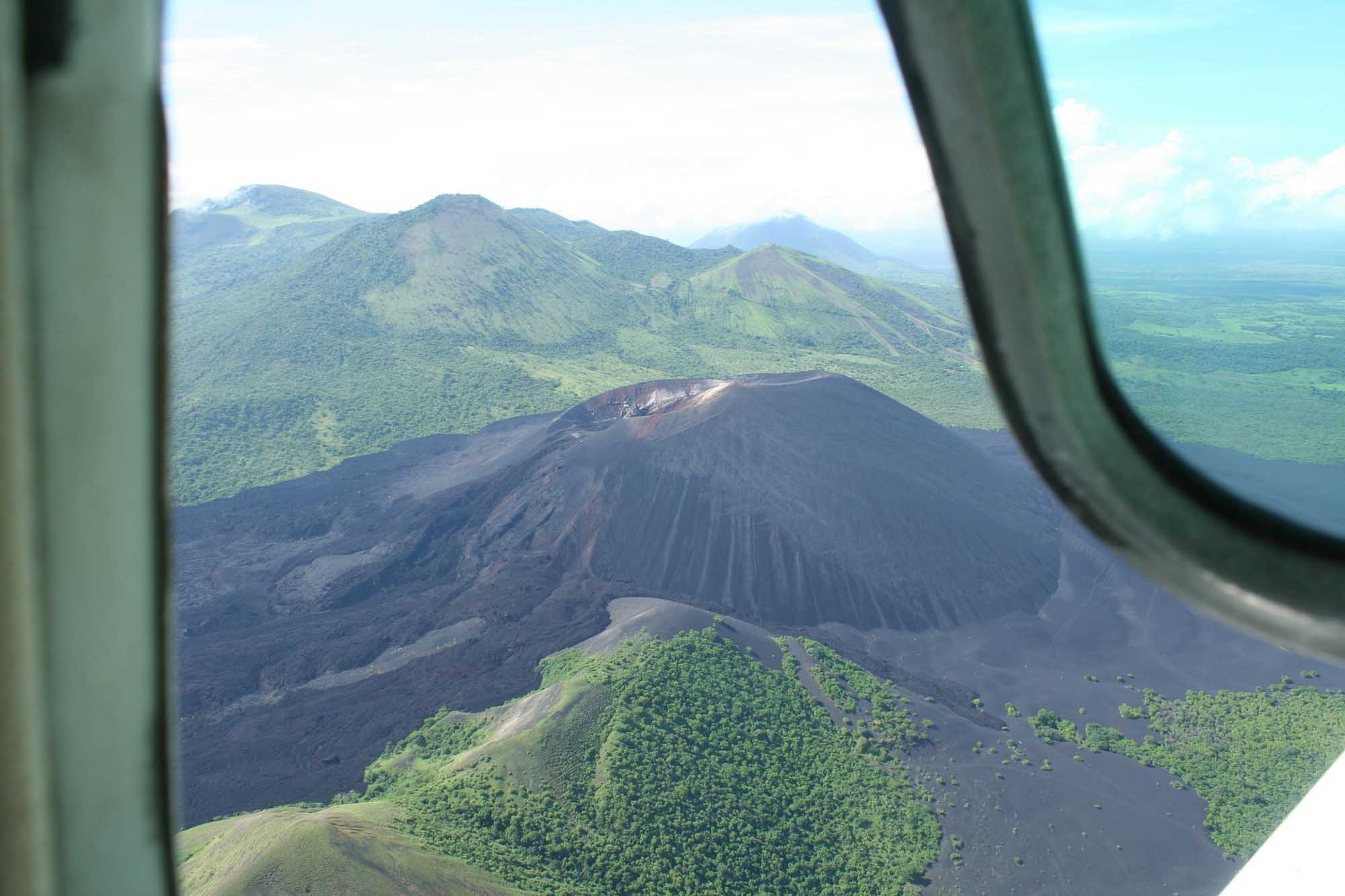 An aerial photograph taken from an aircraft window showing Cerro Negro volcano with its distinctive
