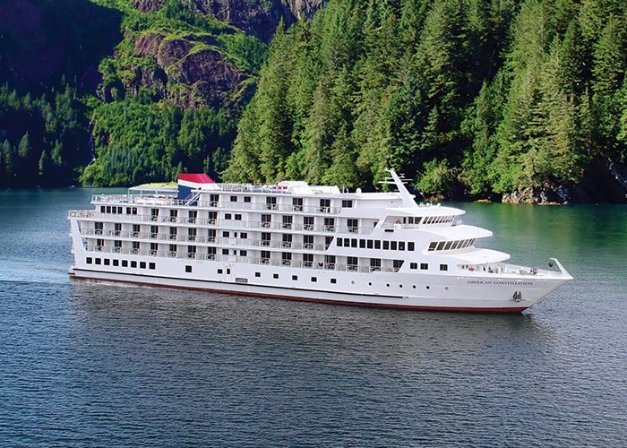 The American Cruise Lines ship Constellation is pictured anchored in a pristine fjord surrounded