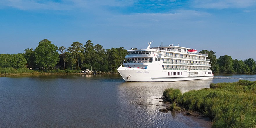 American Cruise Lines River Ship on Waterway A large multi-deck river cruise ship operated by American Cruise Lines navigates a scenic waterway