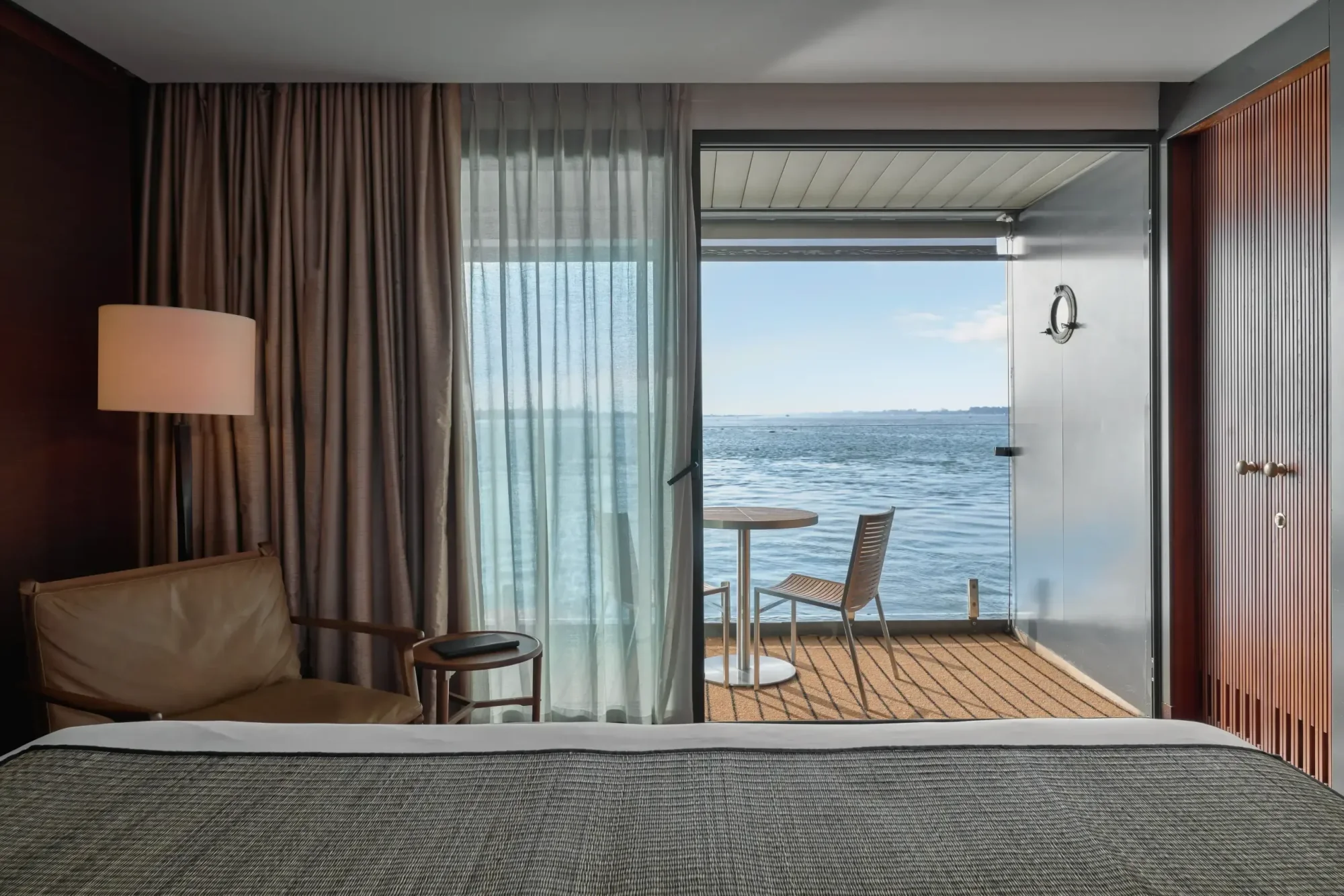 A luxurious design suite aboard an Aqua Expeditions vessel, featuring a modern bedroom