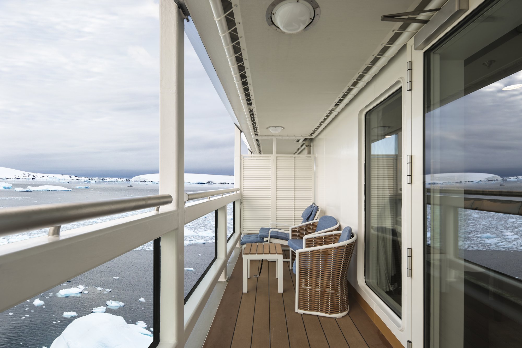 Arctic Balcony Stateroom with Icebergs A spacious balcony stateroom aboard the Douglas Mawson expedition cruise ship, offering panoramic