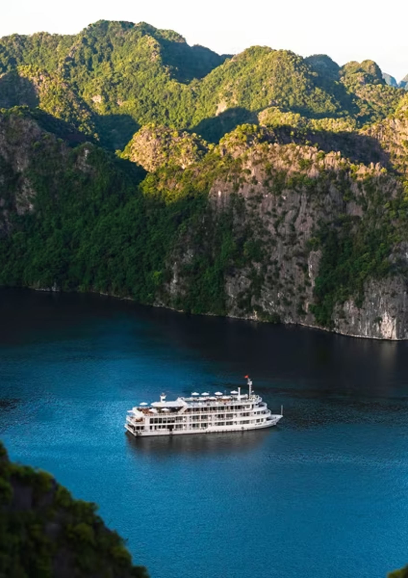 A luxurious expedition cruise ship anchored in the turquoise waters of Halong Bay, surrounded