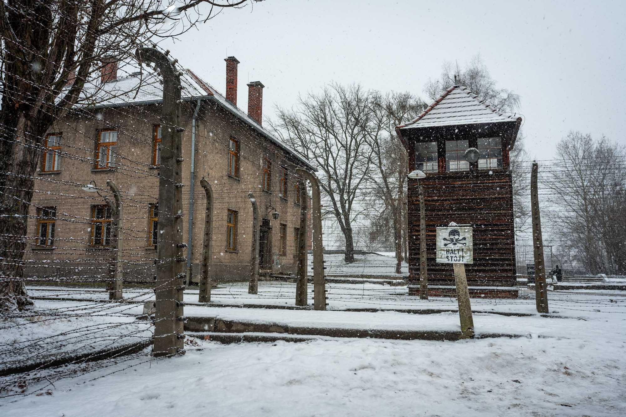 A solemn view of the iconic brick watchtower and barbed wire fences at Auschwitz concentration camp