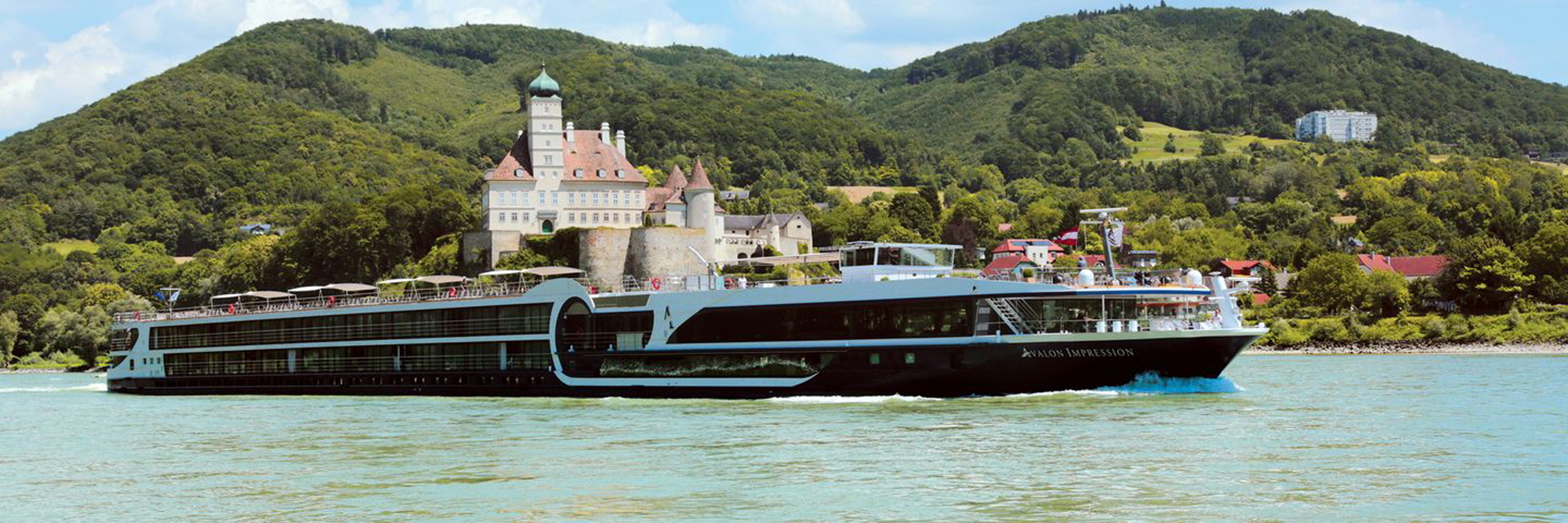 Avalon Impression River Cruise Ship at Danube Castle A modern river cruise ship, the Avalon Impression, navigates the Danube River with a picturesque