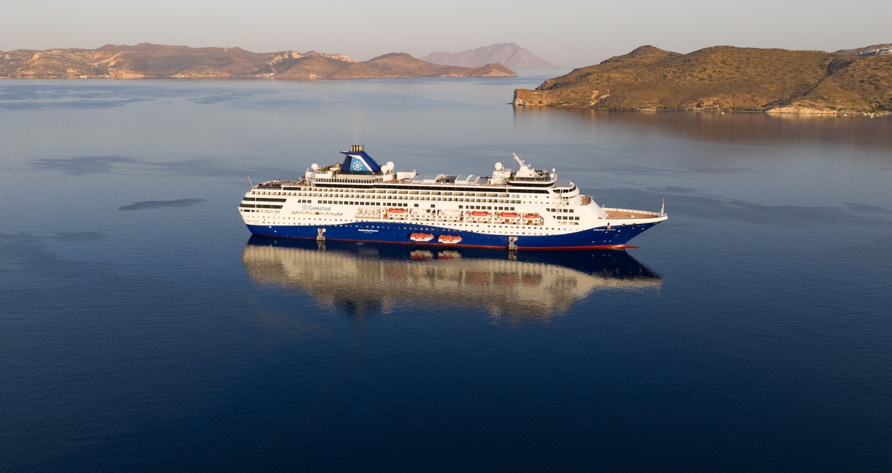 Celestyal Cruises Ship in Mediterranean Waters A large cruise ship operated by Celestyal Cruises anchored in calm Mediterranean waters, with arid