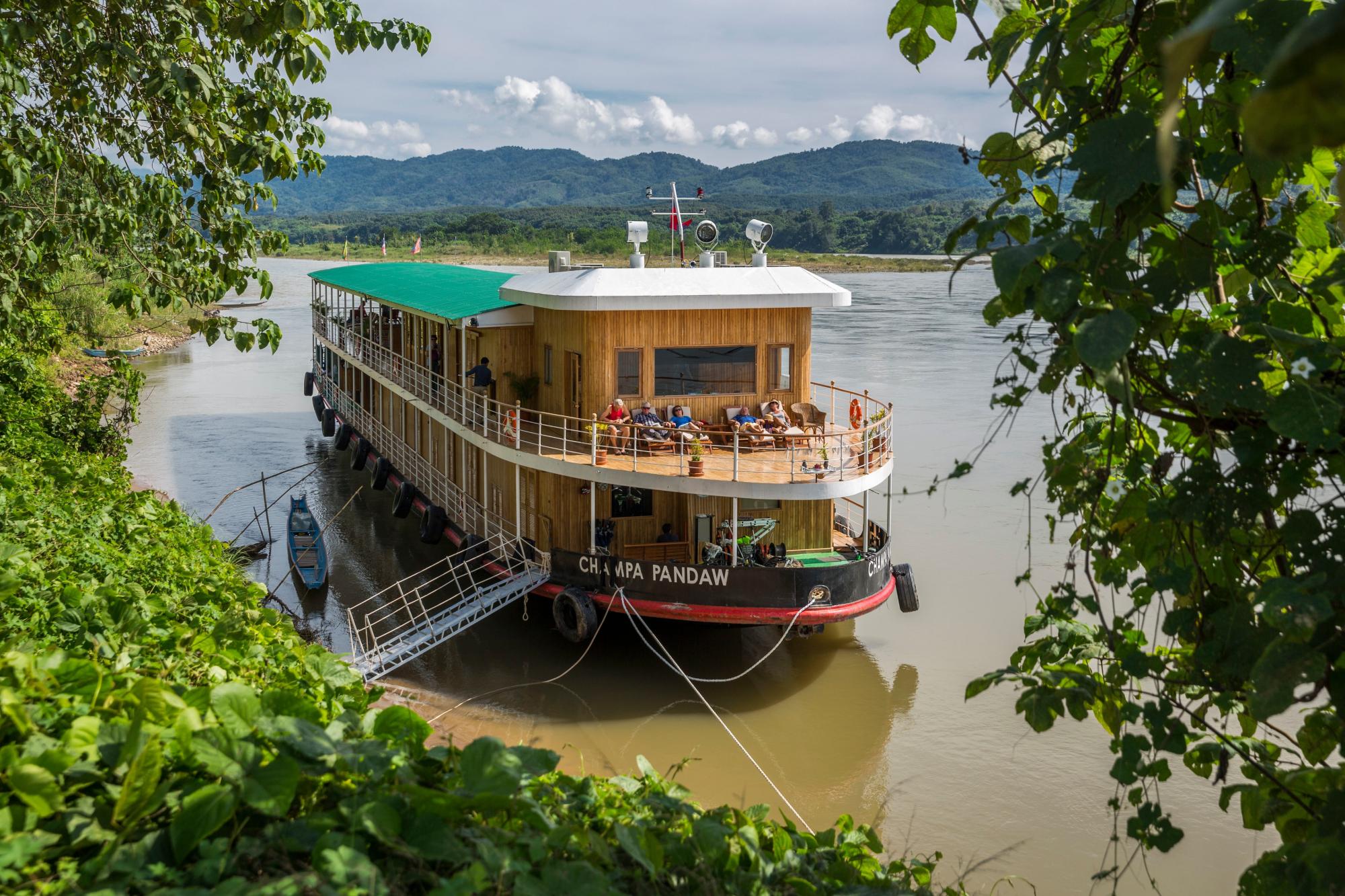The Champa Pandaw, a luxury river cruise vessel, is moored along the Mekong River with passengers