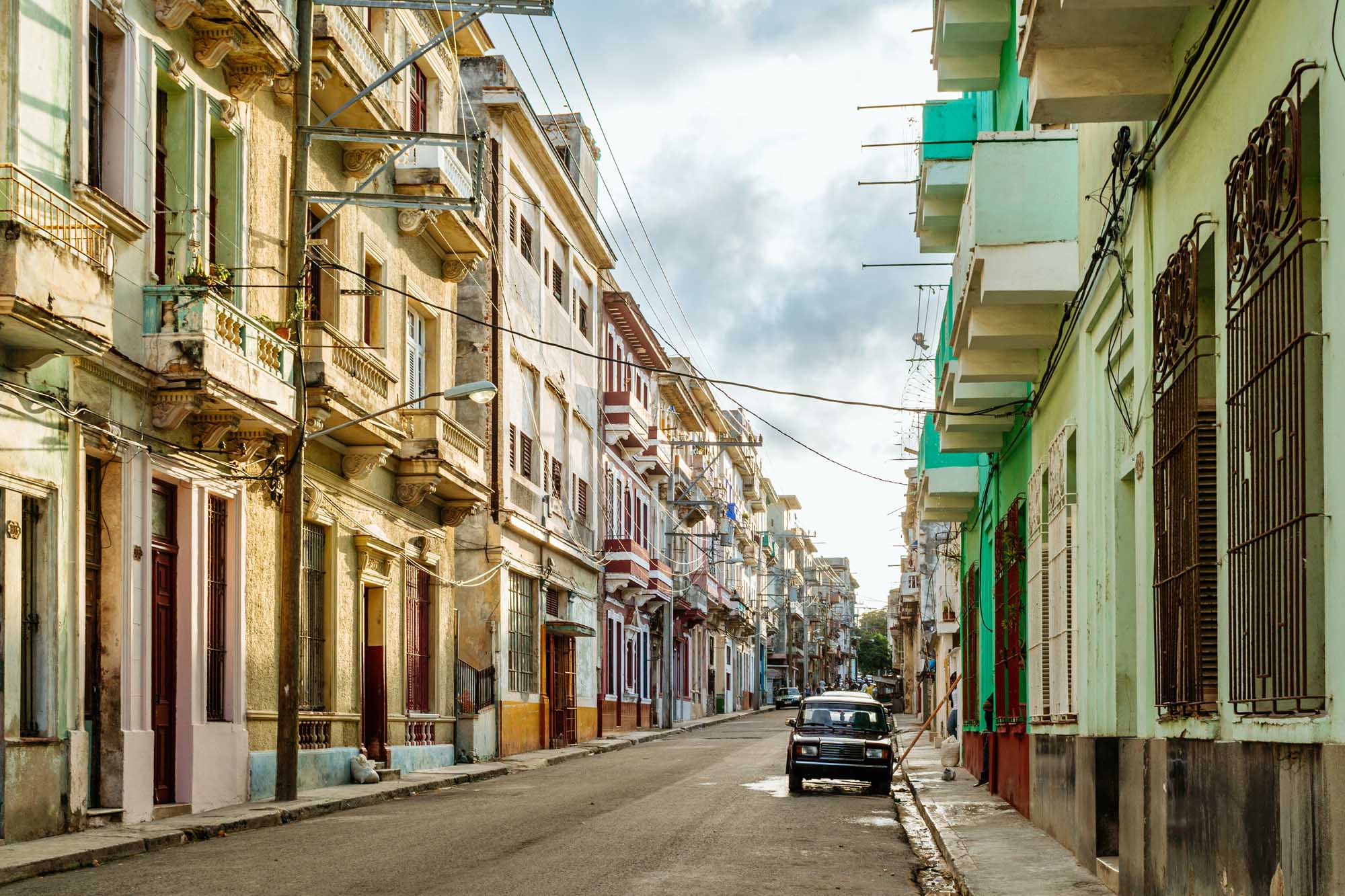 Colorful Colonial Street in Havana, Cuba A vibrant street scene in historic Havana lined with pastel-colored colonial buildings featuring