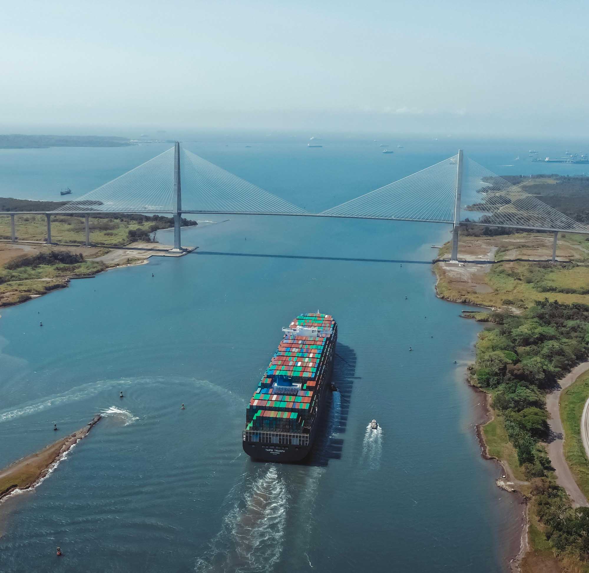 Container Ship Transiting Panama Canal Bridge A large container ship laden with colorful cargo containers navigates through the Panama Canal